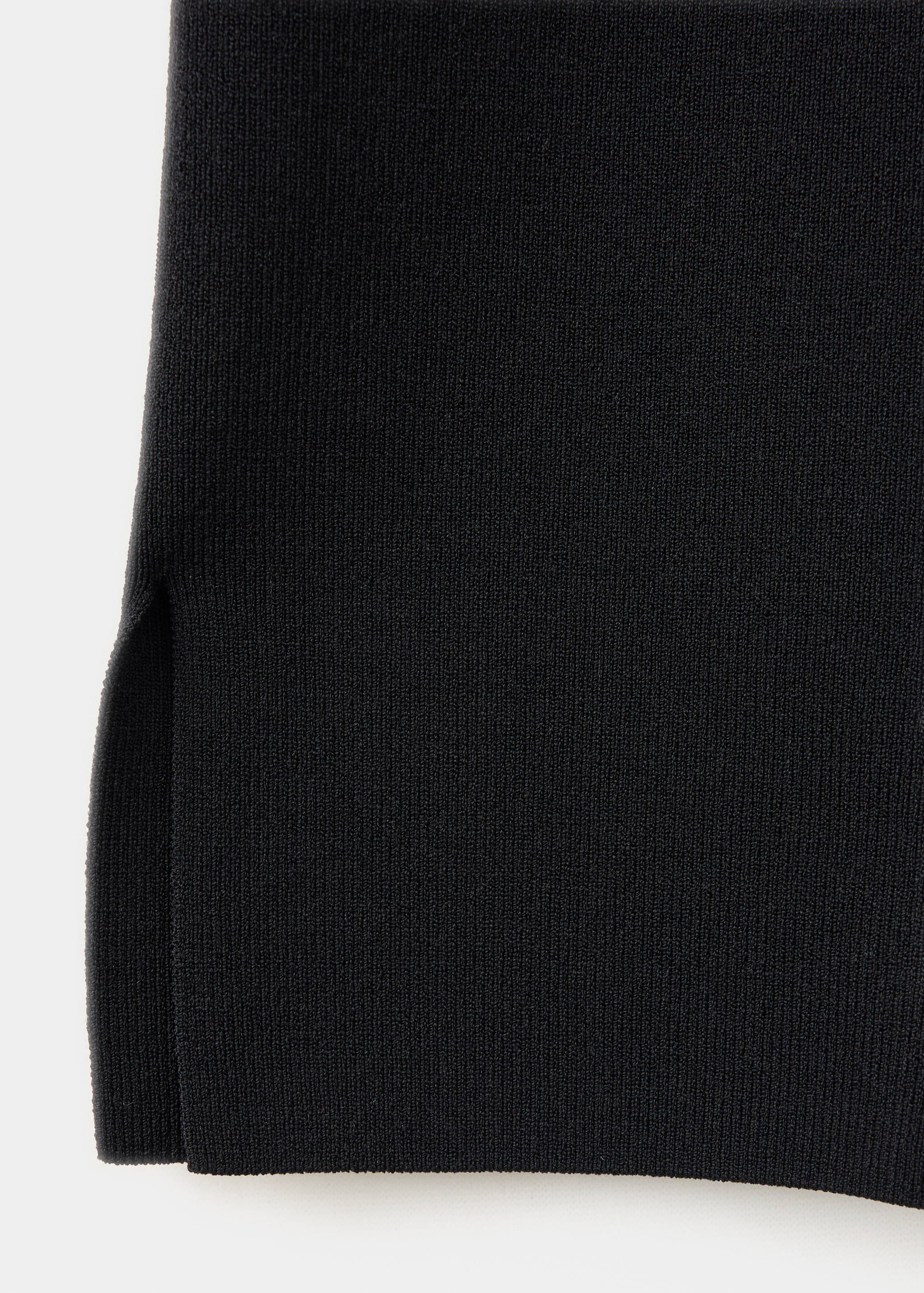 Close-up of black knitted trousers showing fine texture and hem detail.