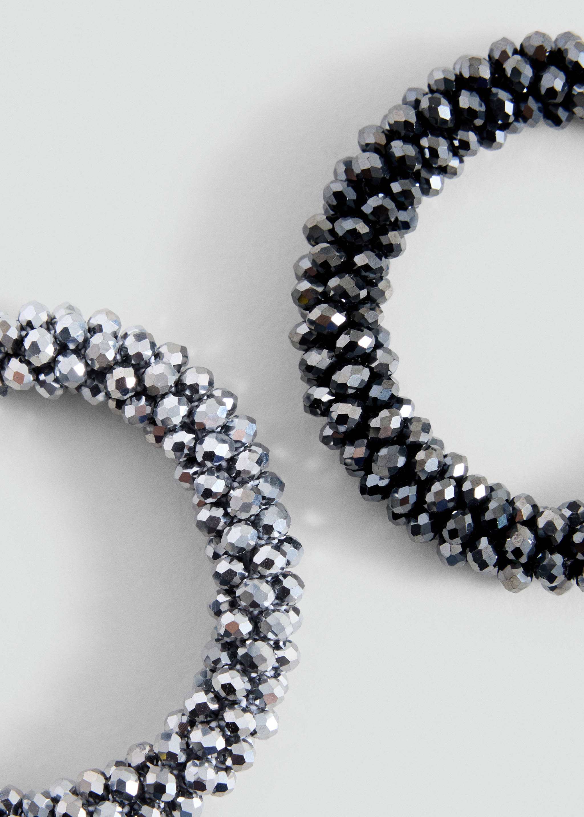 Close-up of two sparkling beaded bracelets in dark grey and silver.
