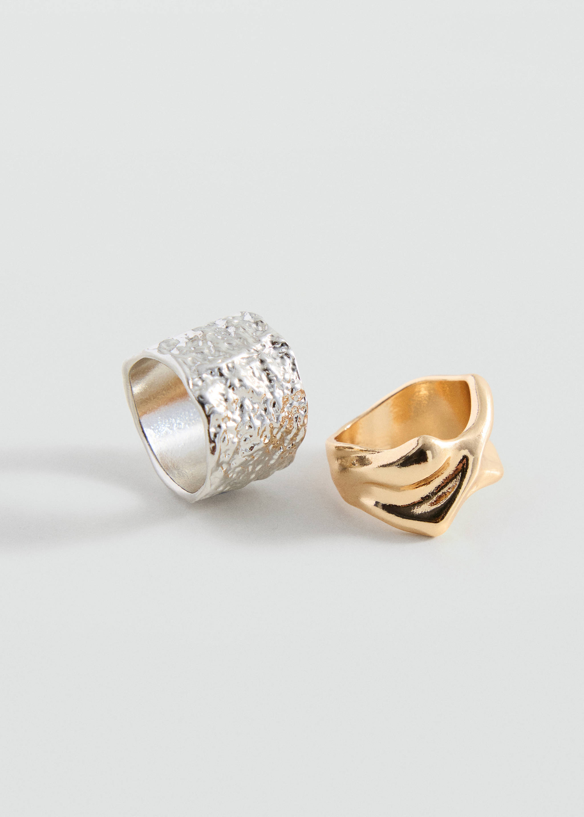 Set of two textured rings in silver and gold with organic shapes.