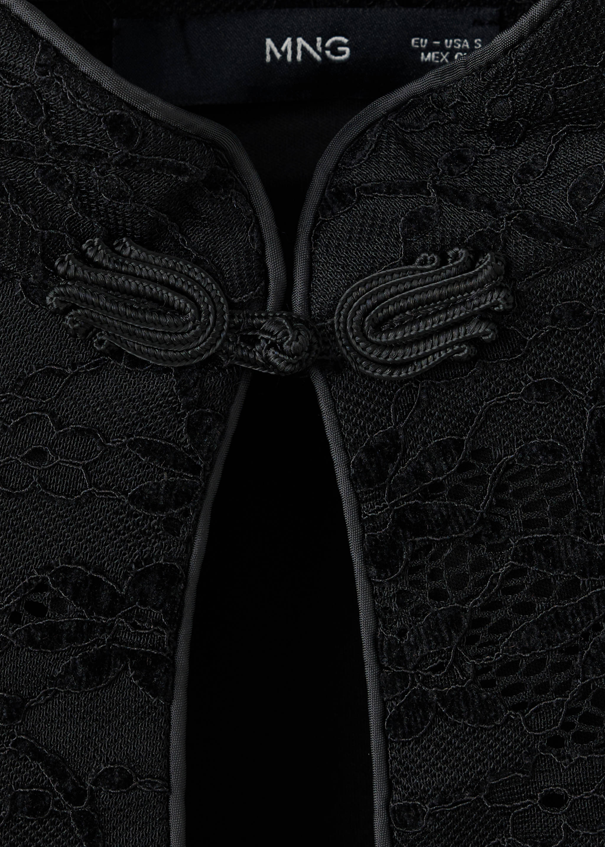 Close-up of a black lace dress with a Mandarin collar and frog closures.