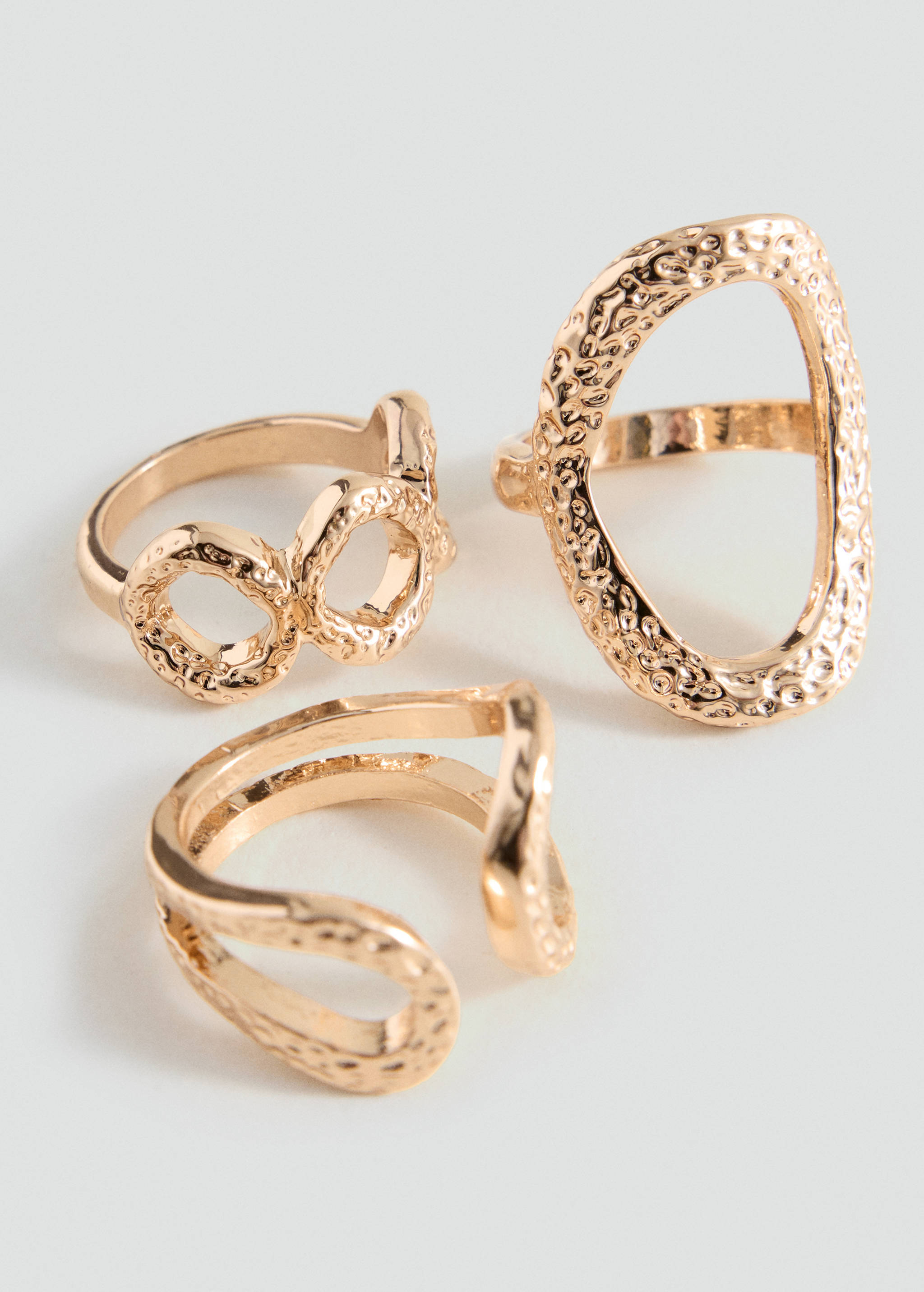 Set of three textured gold-coloured rings with distinct open and geometric shapes.