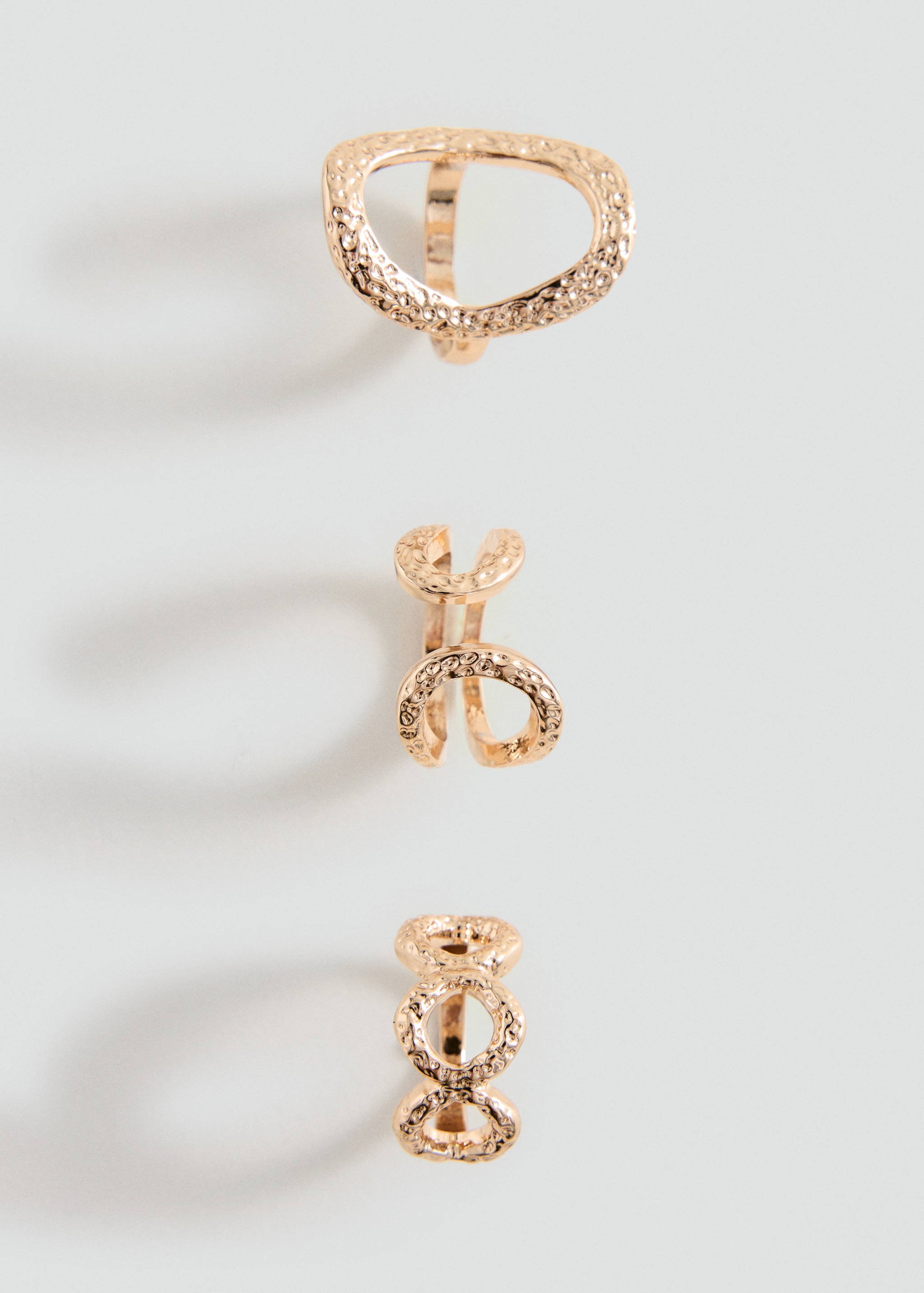 Set of three textured gold-coloured metallic rings with distinct geometric designs.