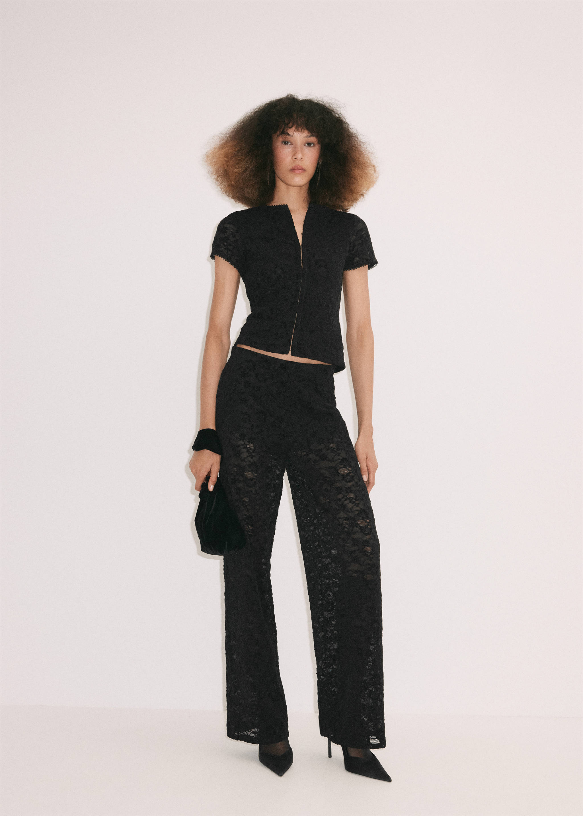 Black lace trousers, worn with a matching short-sleeved top and black accessories.