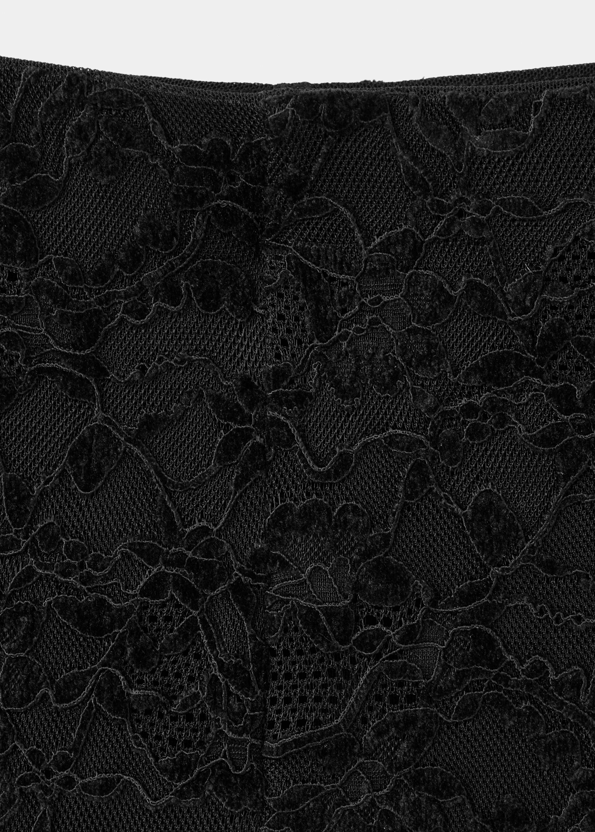 Close-up of black lace trousers showing the intricate floral pattern.