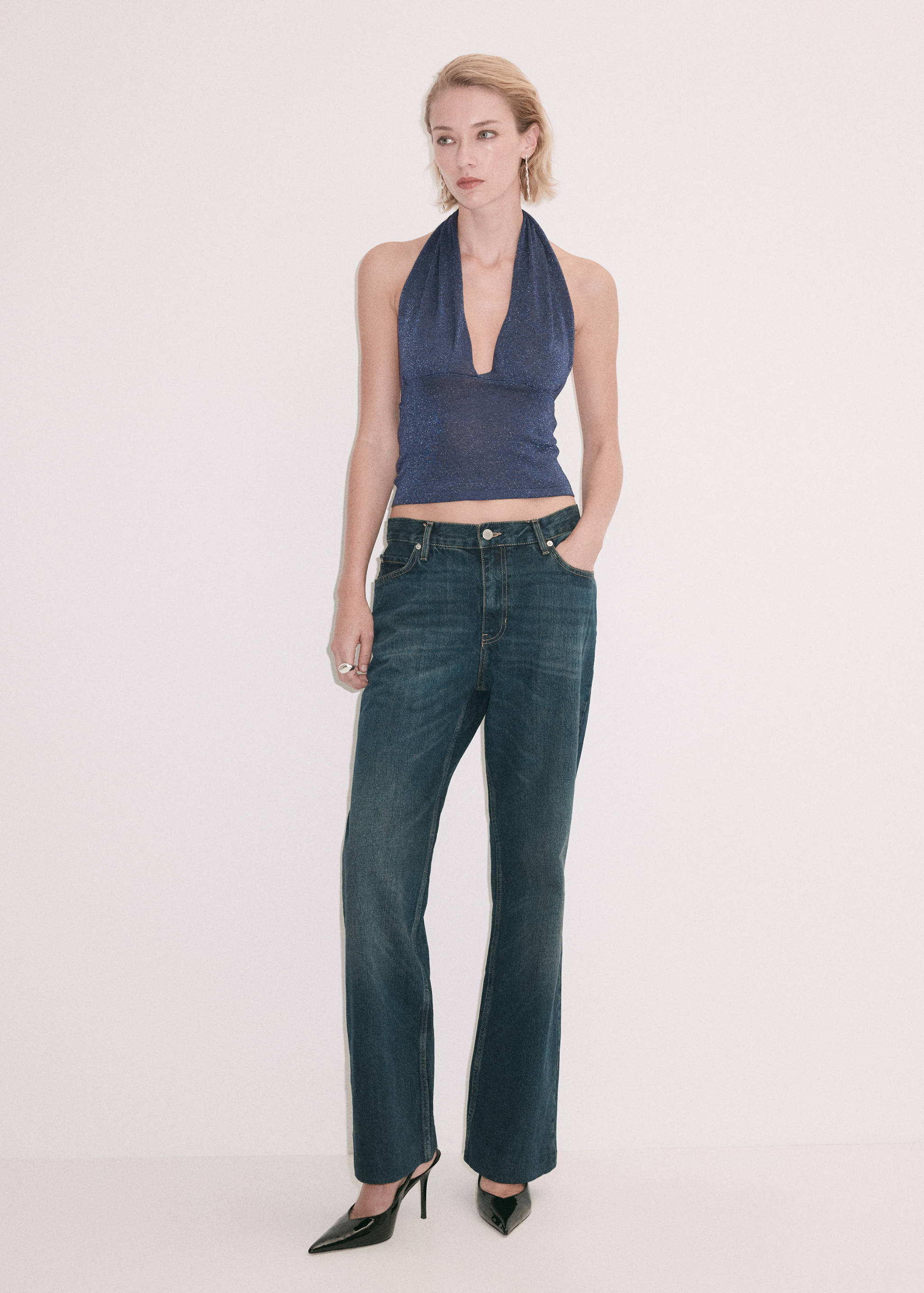 Blue metallic halter top paired with dark blue denim trousers.