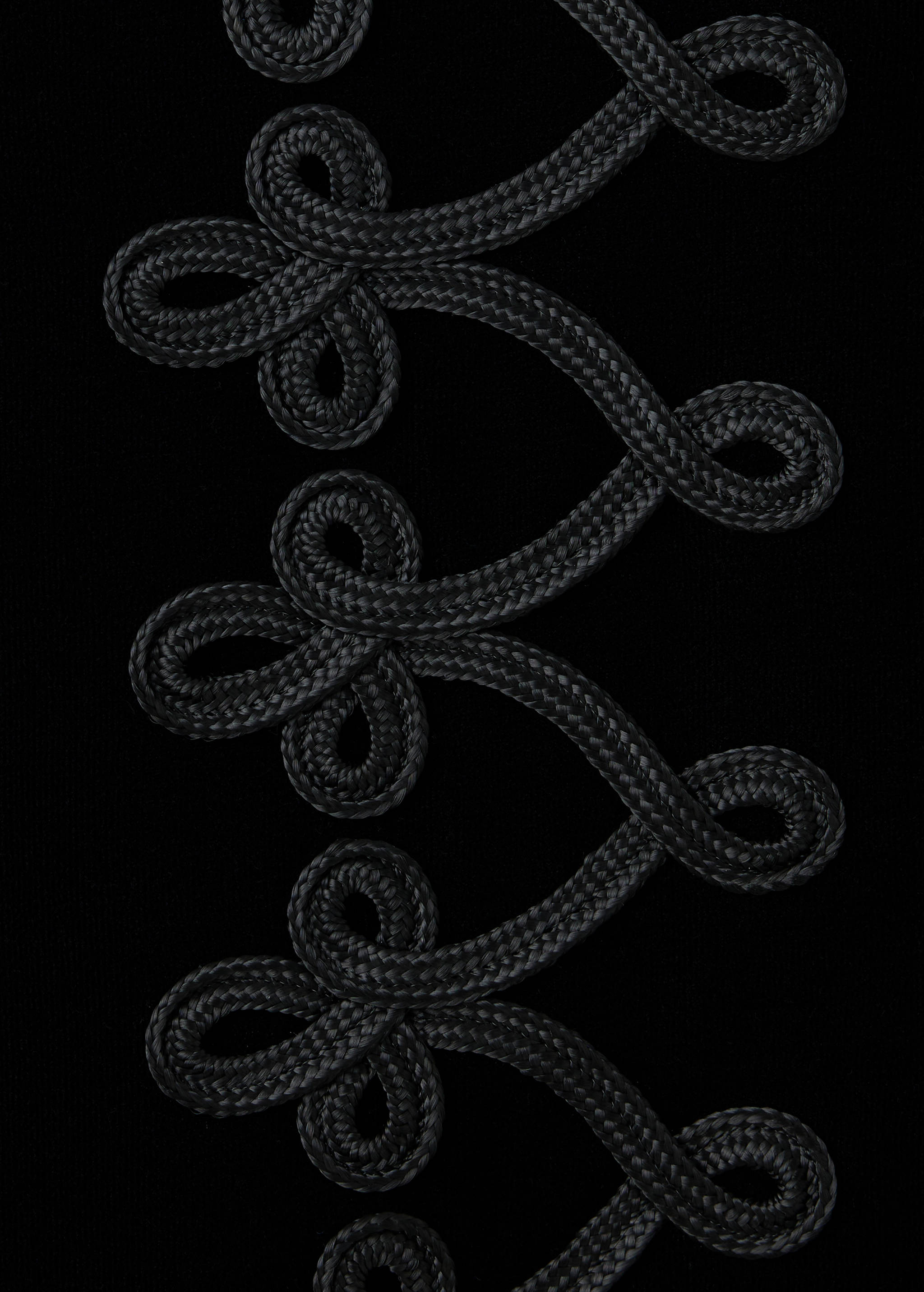Close-up of a black jacket featuring decorative braided trim.