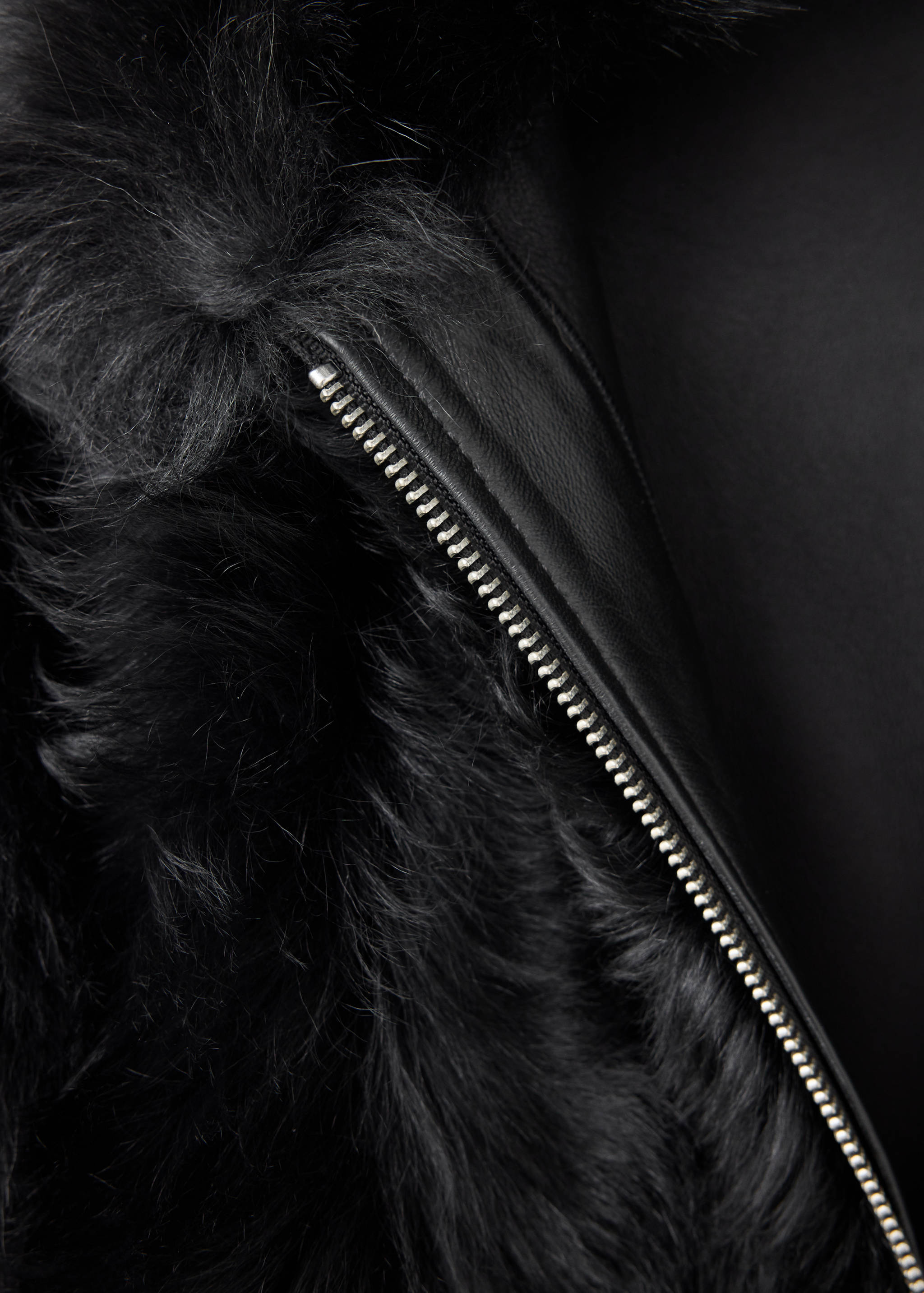 Close-up of a black jacket with faux-fur collar and zip detail.
