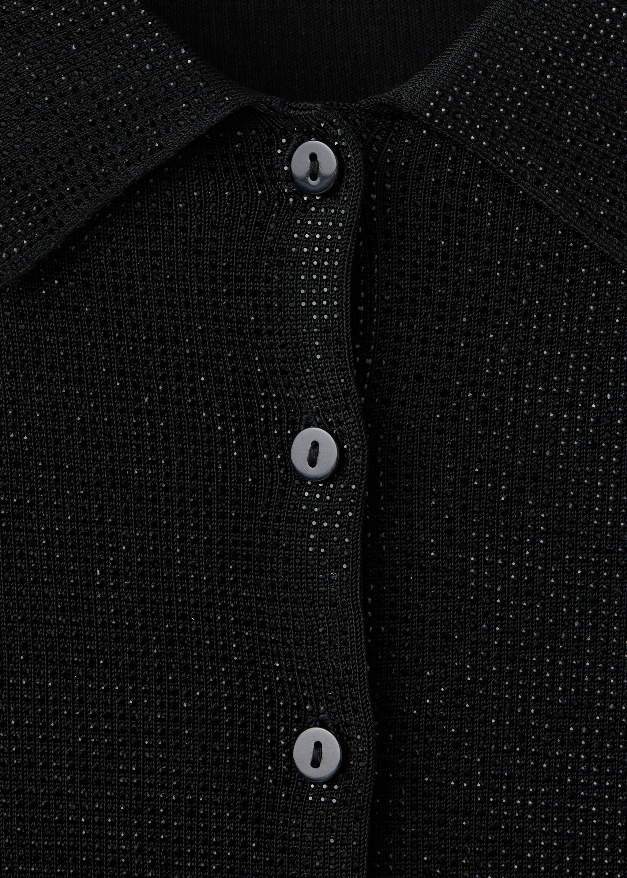 Detalle de cárdigans de punto negro con cuello de picos y botonadura.