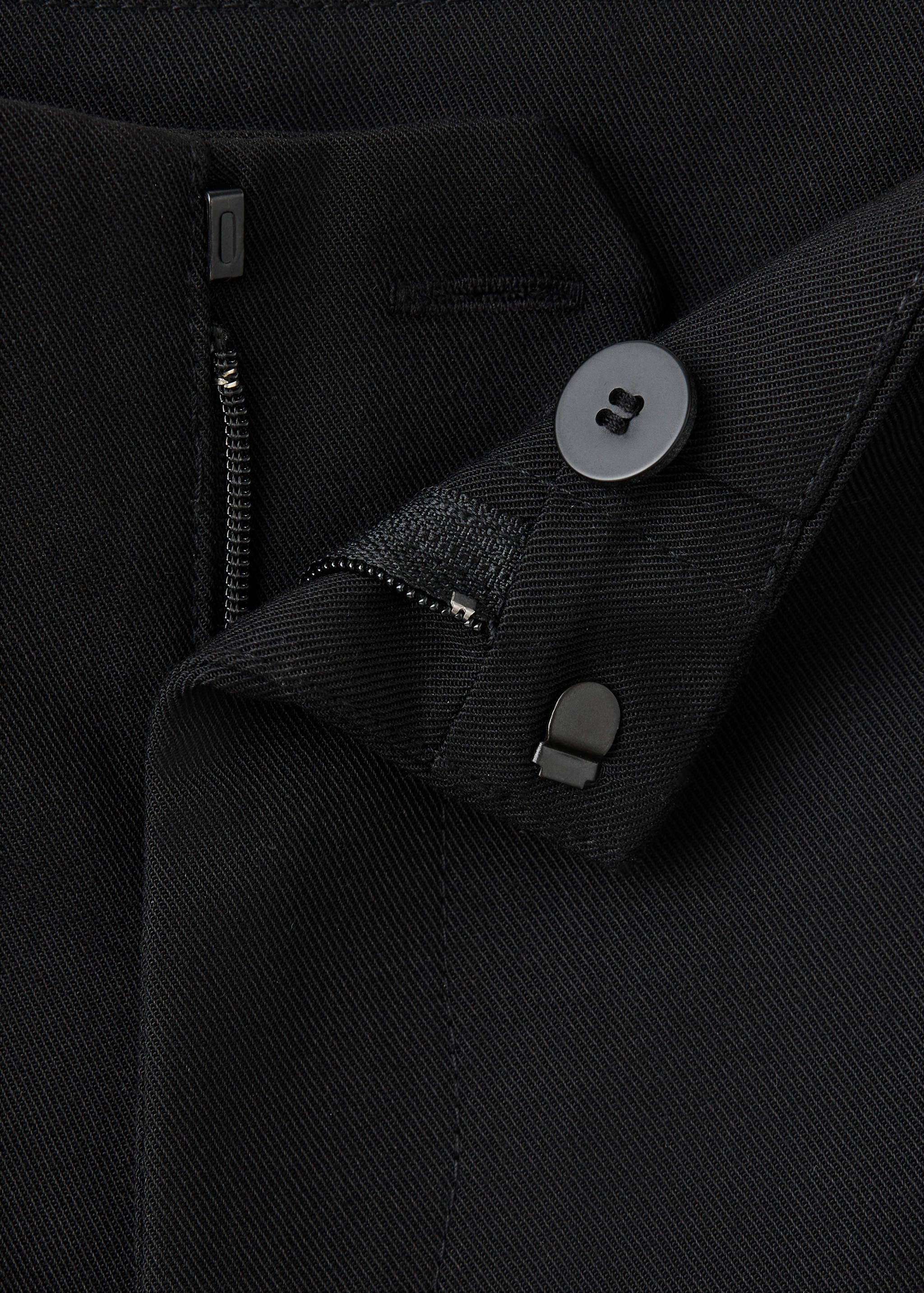Black shorts fabric detail with a button, zip fly, and hook-and-bar closure.