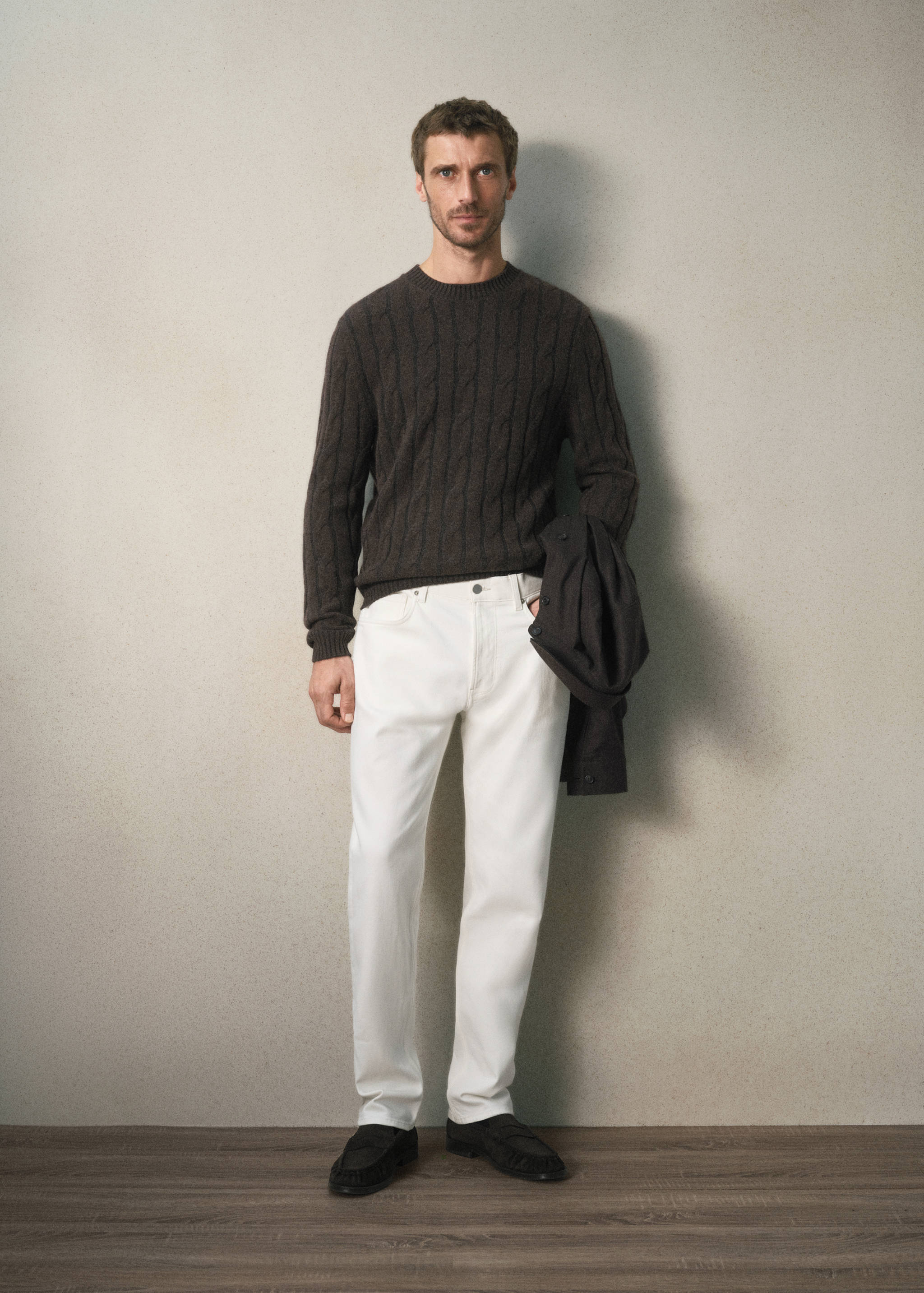 White trousers worn with a dark brown cable-knit sweater.