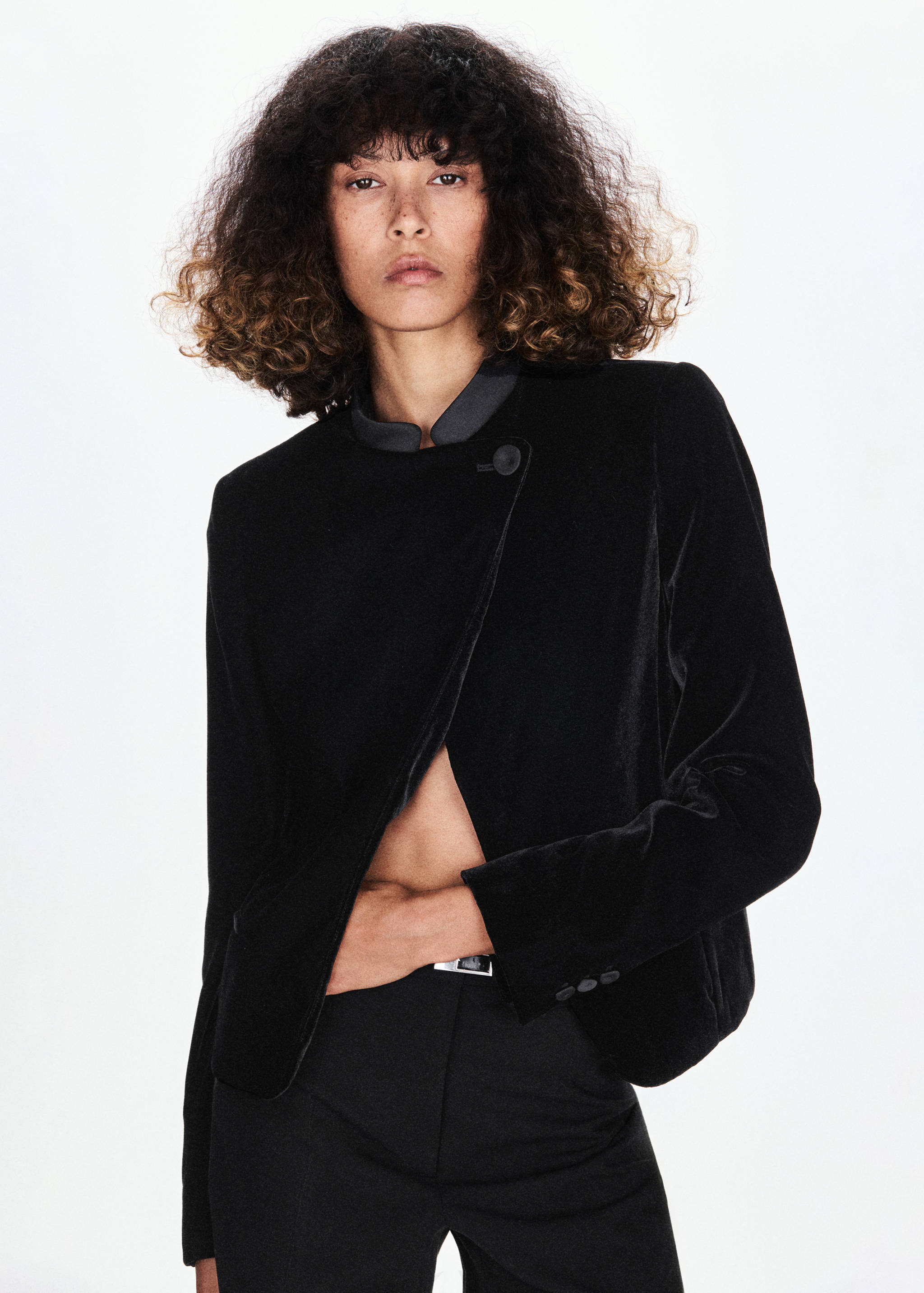 Blazer de terciopelo negro con cierre de botones asimétrico y cuello mao.