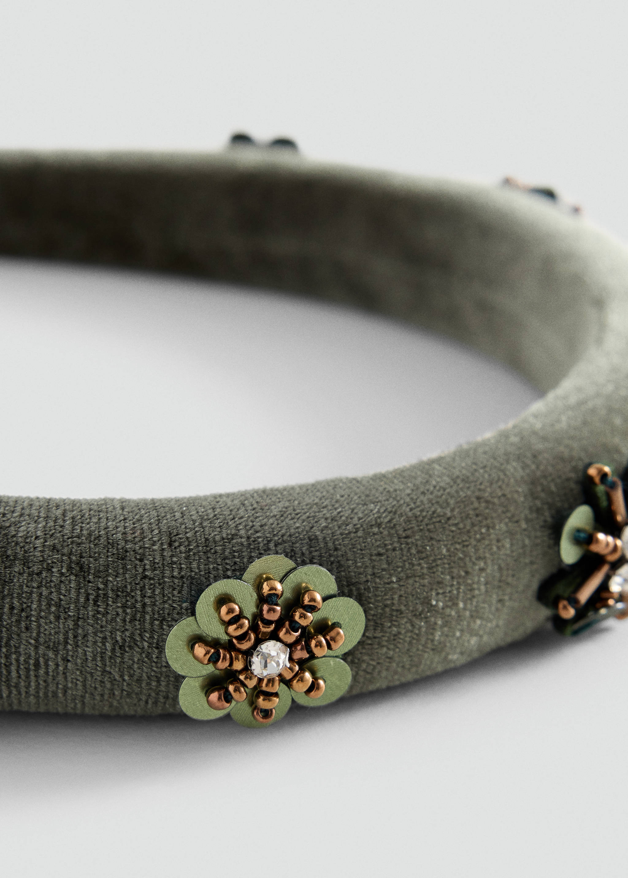 Close-up of a green velvet headband with beaded floral embellishments.