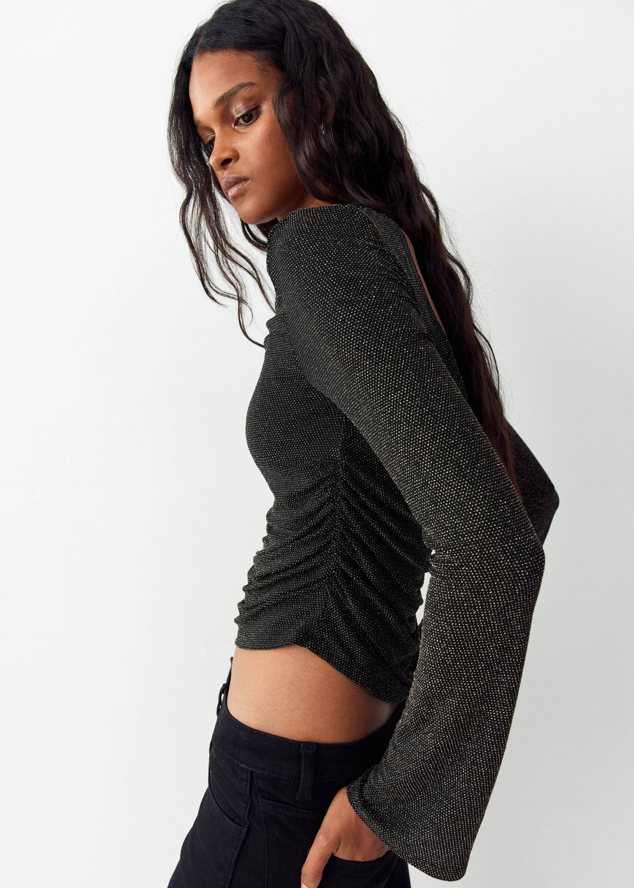 Sparkling black t-shirt with boat neckline, ruching, and long flared sleeves.
