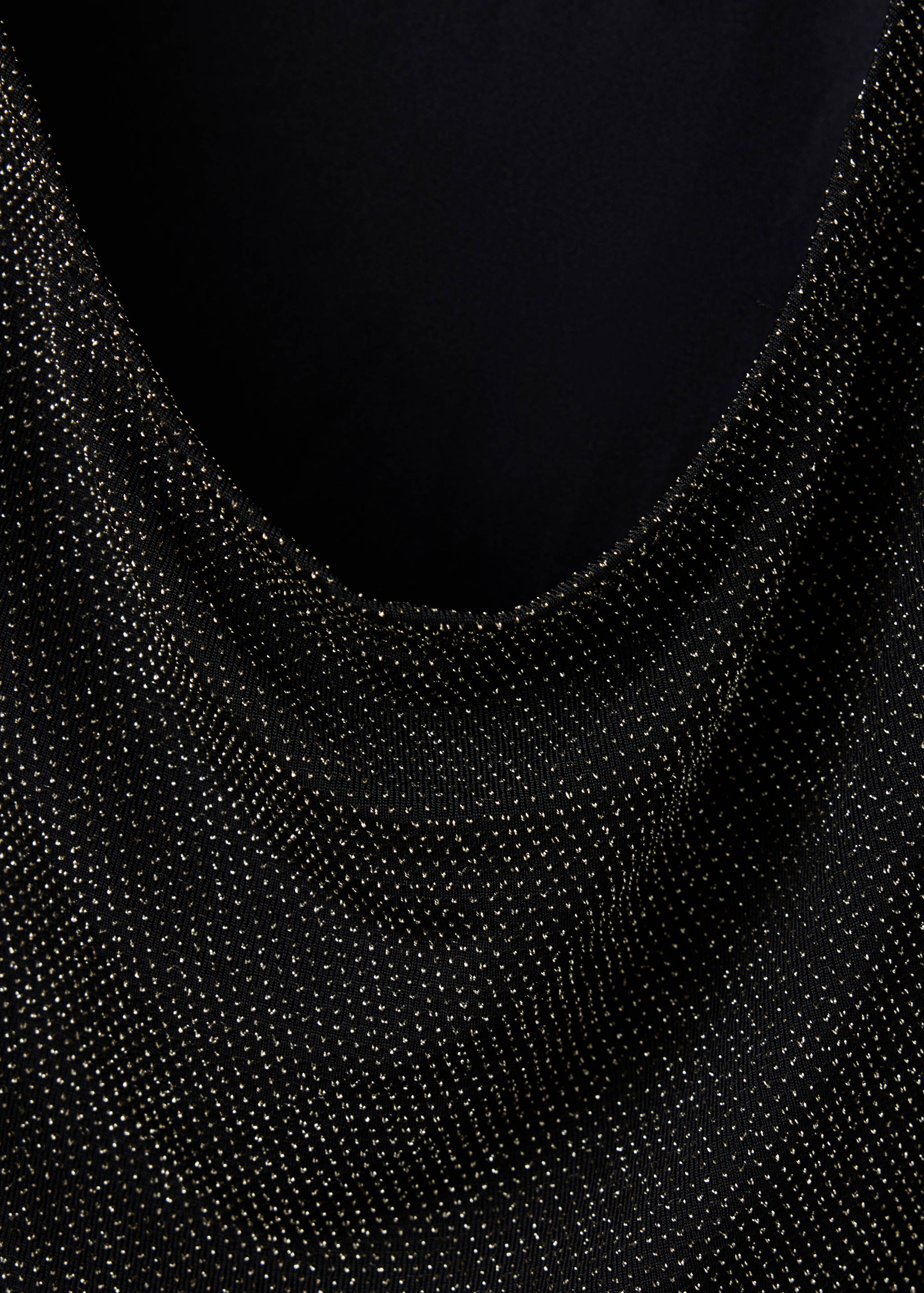 Close-up of a black t-shirt fabric with a glittering gold metallic finish and cowl neckline.