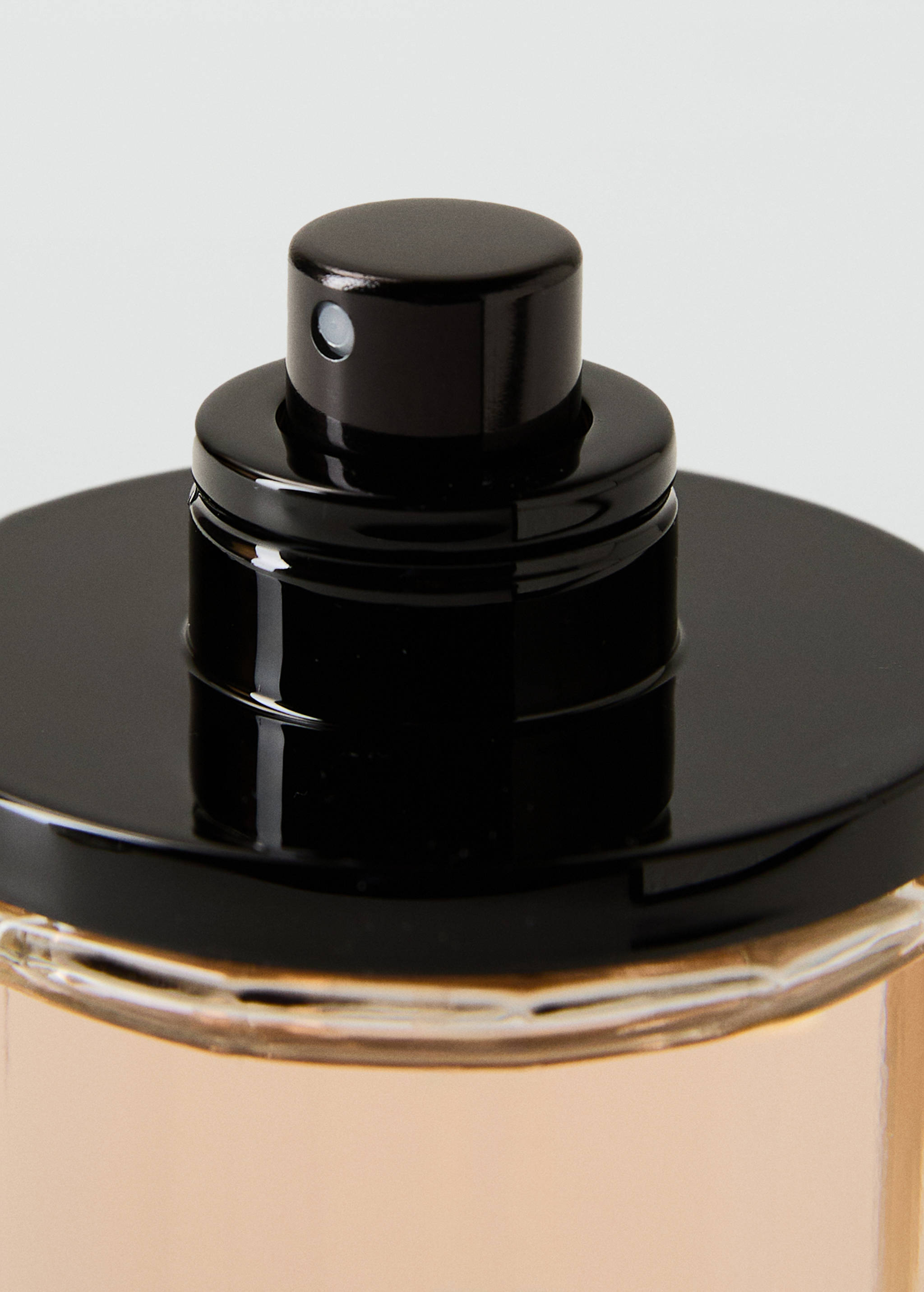 Close-up of a black fragrance bottle cap and spray nozzle.