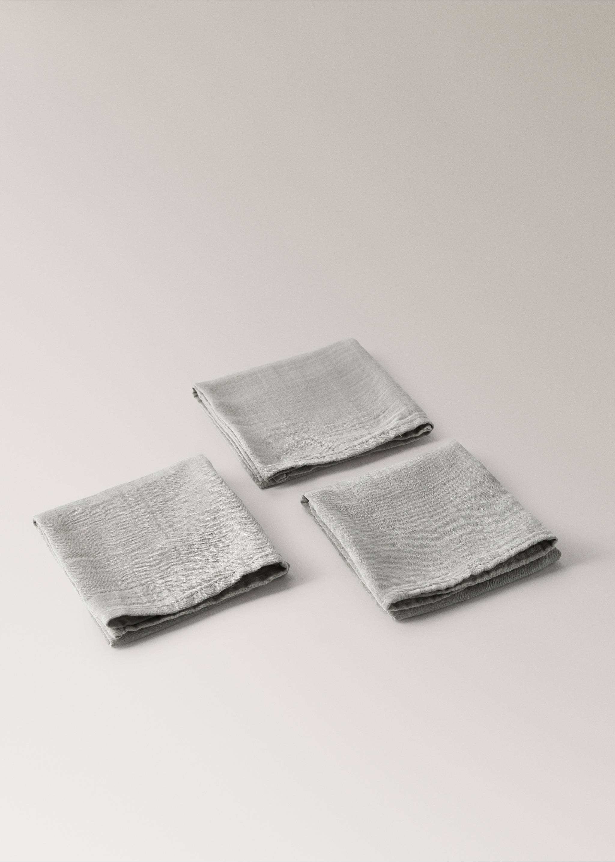 Three folded light grey muslin swaddle blankets on a neutral surface., Medium Brown. Ref: 37161572-00.