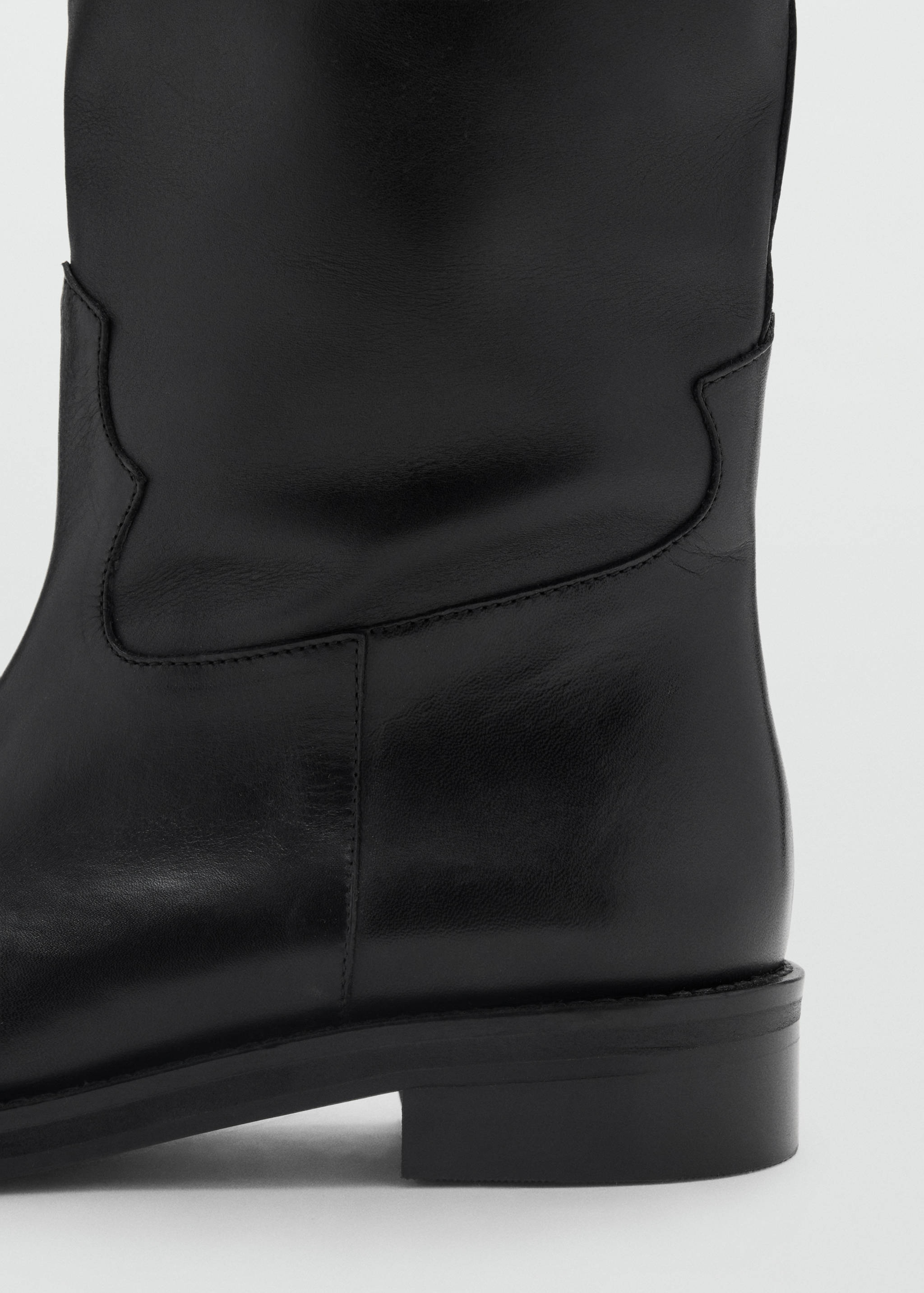 Close-up of a black leather boot with tonal stitching and a low heel.