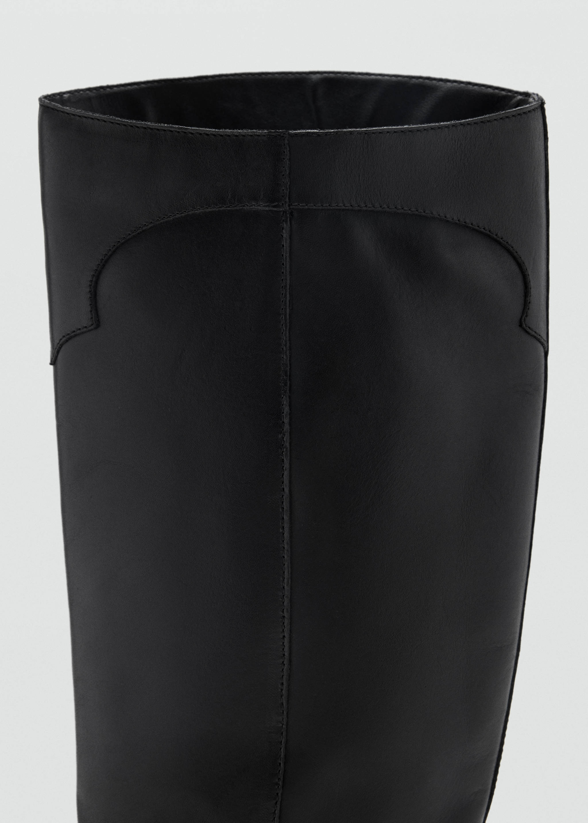 Close-up of the upper shaft of a black boot with decorative stitching.