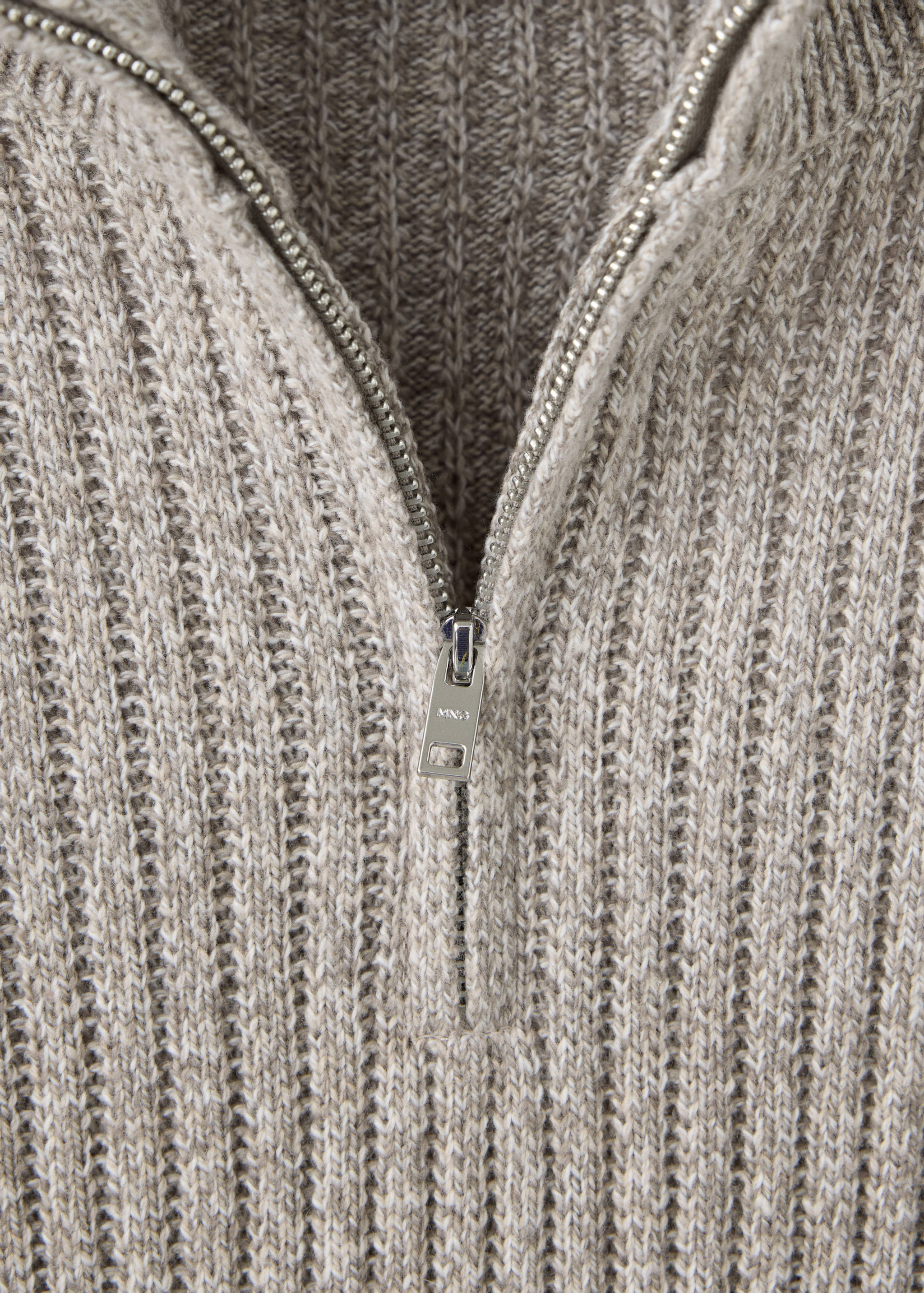 Close-up of a beige marled ribbed knit jersey with a zip-neck detail.