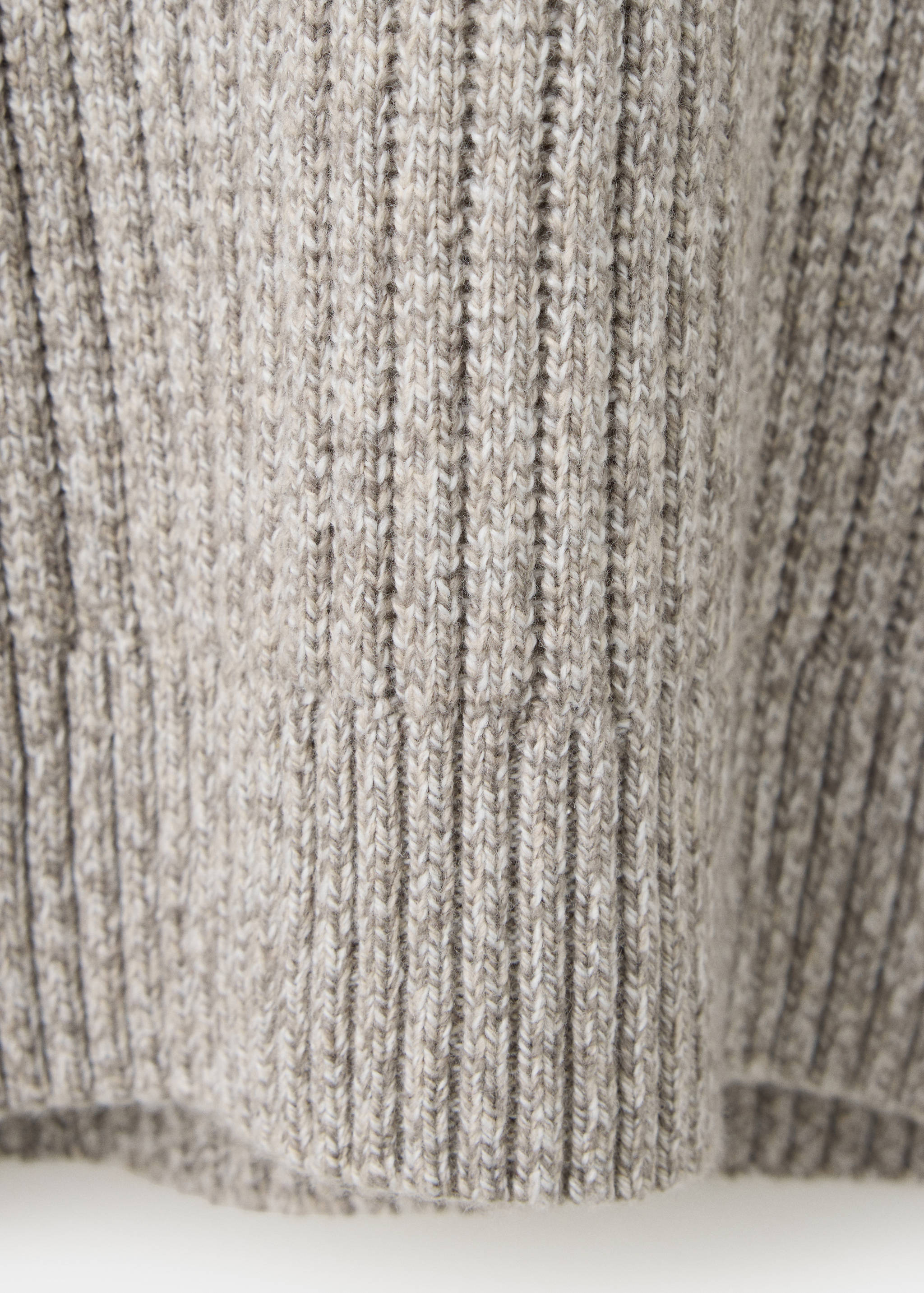 Close-up of a mottled beige knitted jersey fabric with vertical ribs.