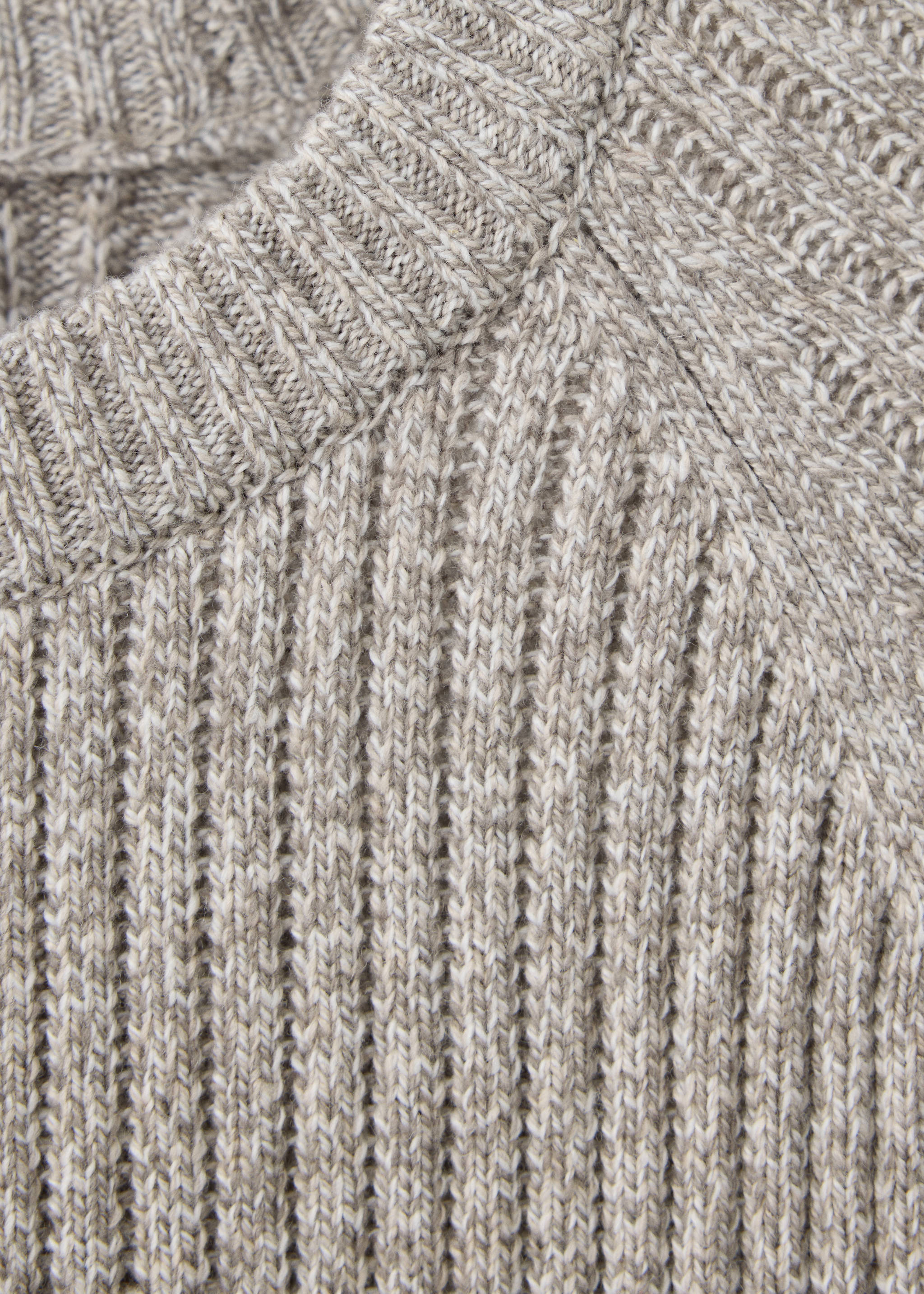 Close-up of a beige knitted jumper showing the ribbed crew neckline and texture.