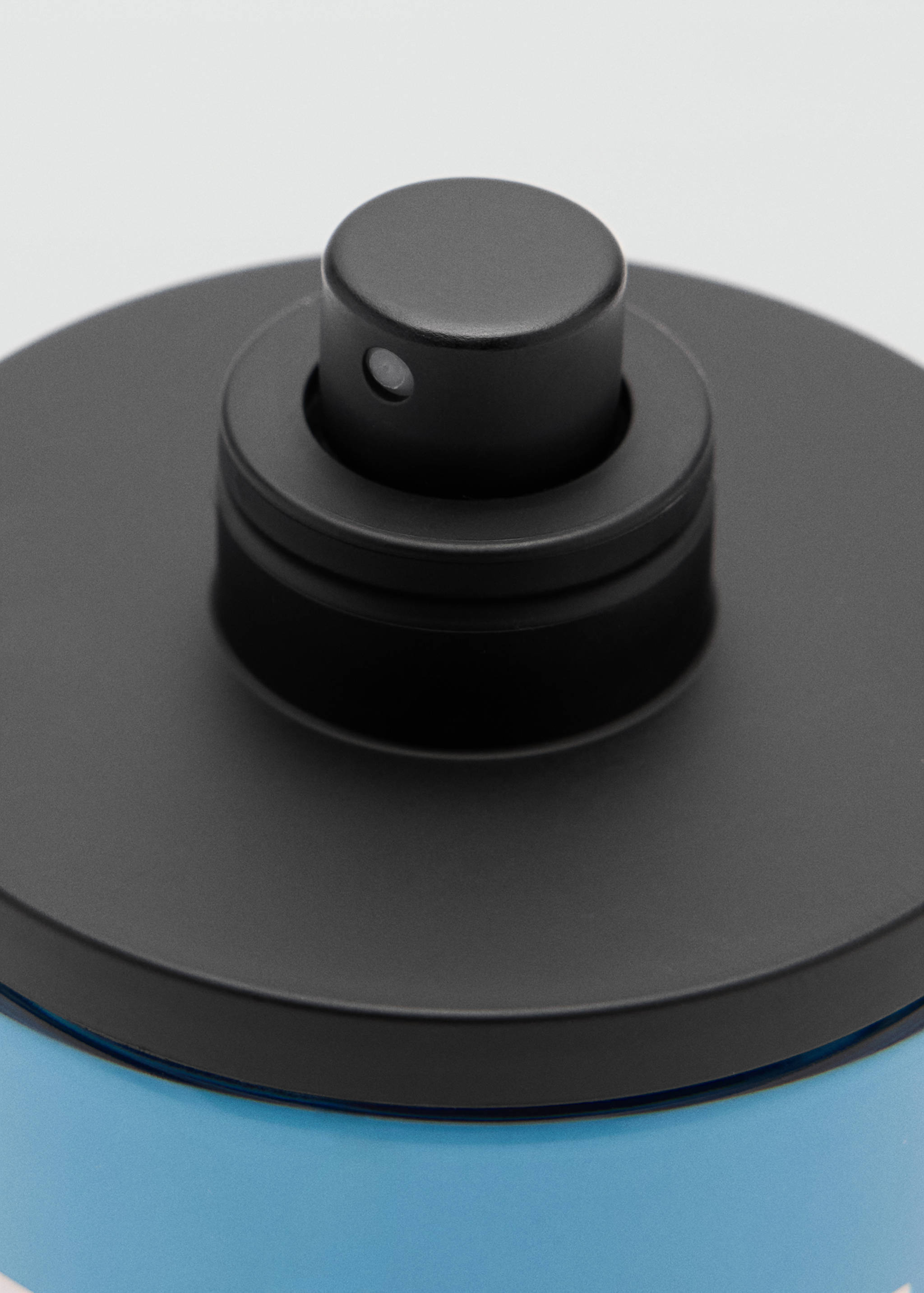 Close-up of a men's perfume bottle with a black cap and blue base.