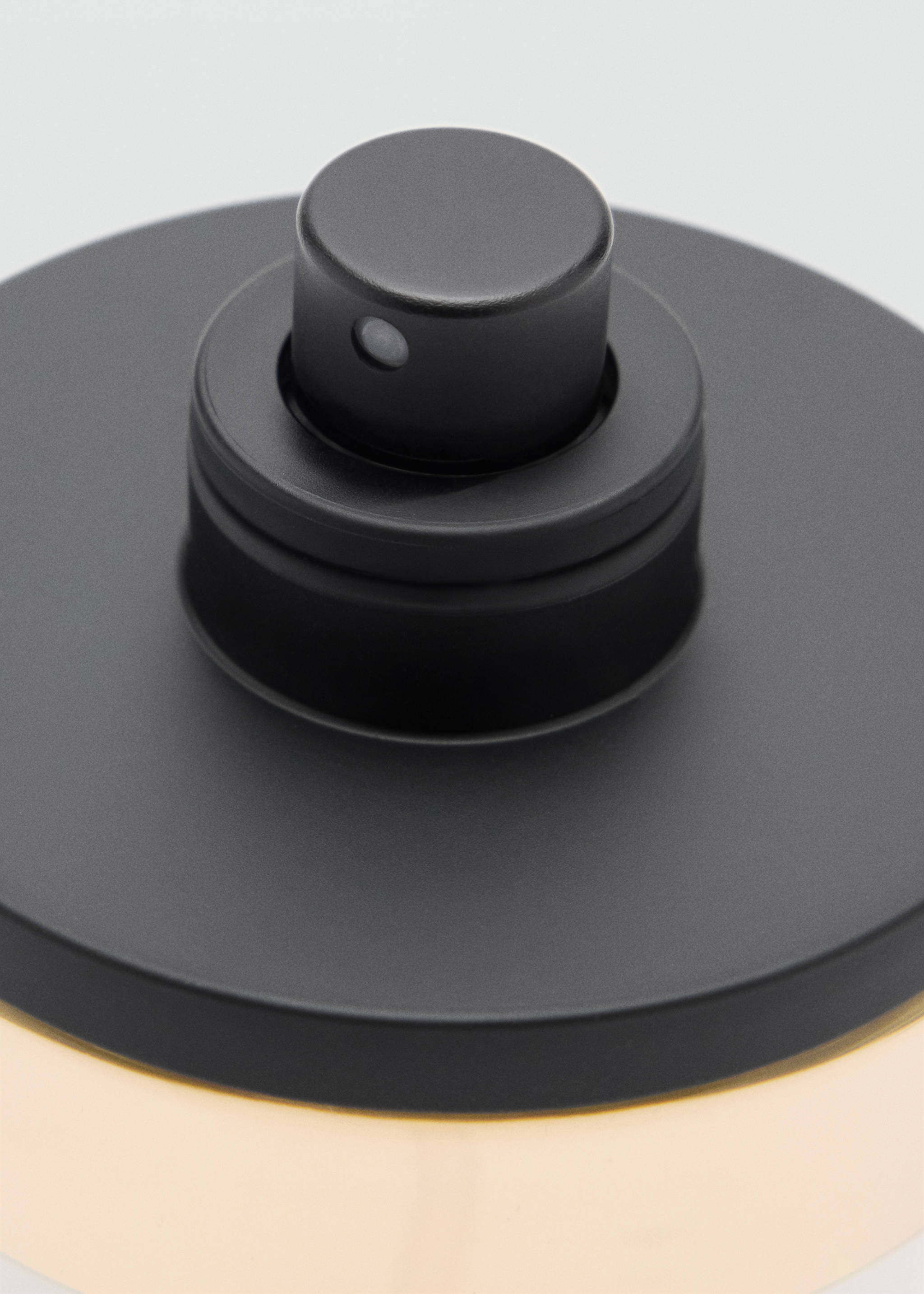 Close-up of a men's perfume bottle with a matte black spray nozzle.