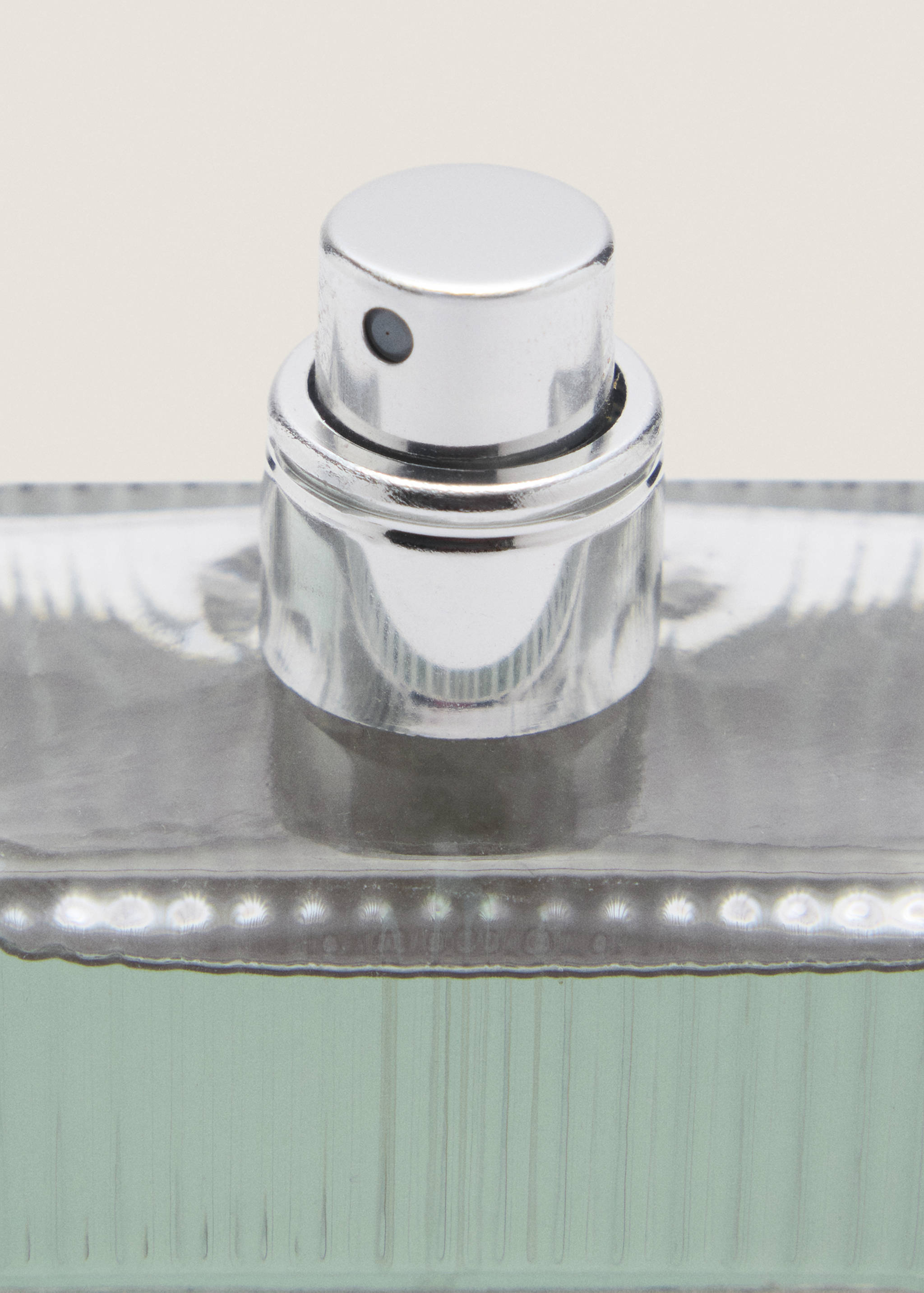 Close-up of a men's perfume bottle showing the silver spray nozzle.