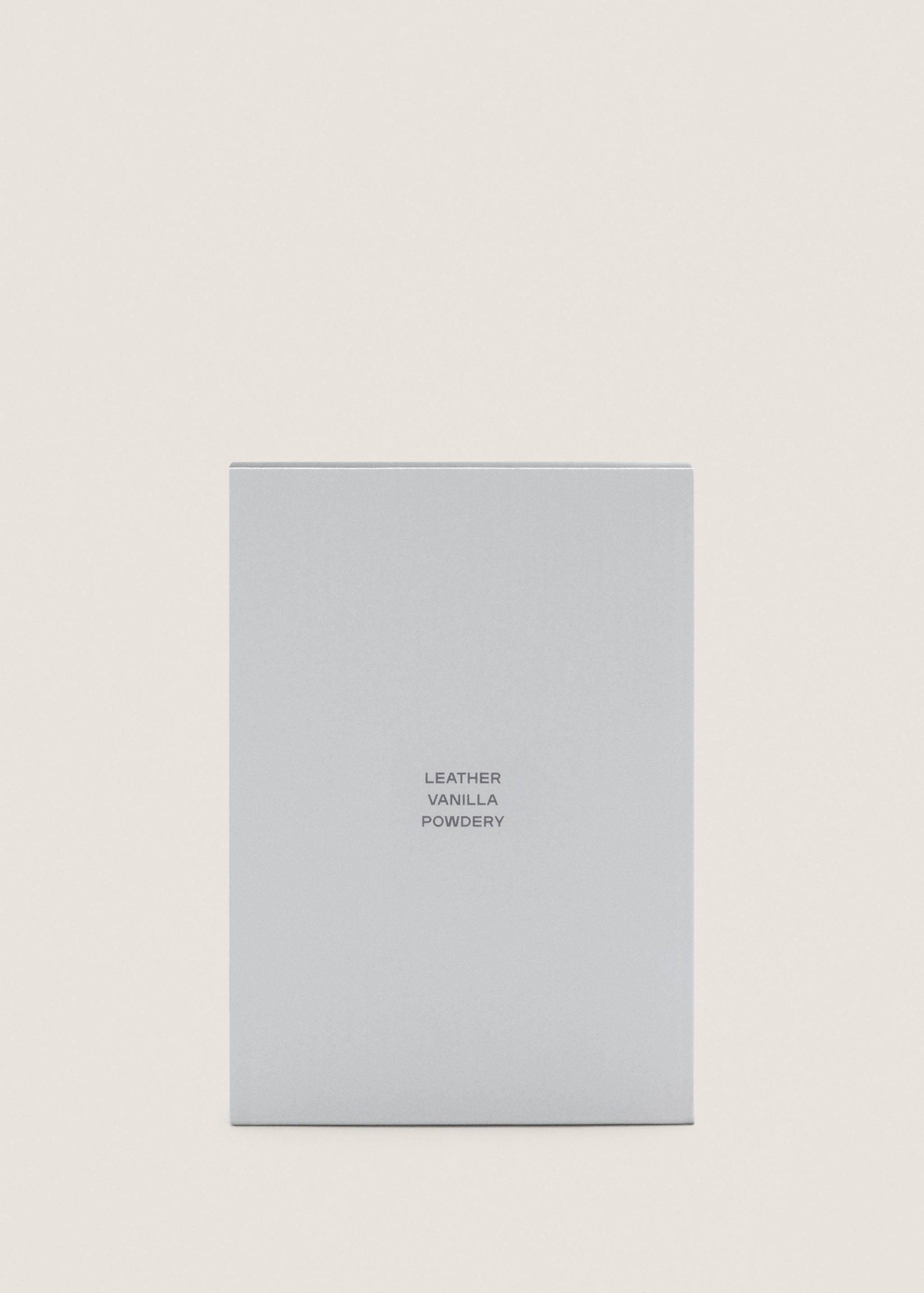 Close-up of a light grey perfume box with leather, vanilla and powdery text.