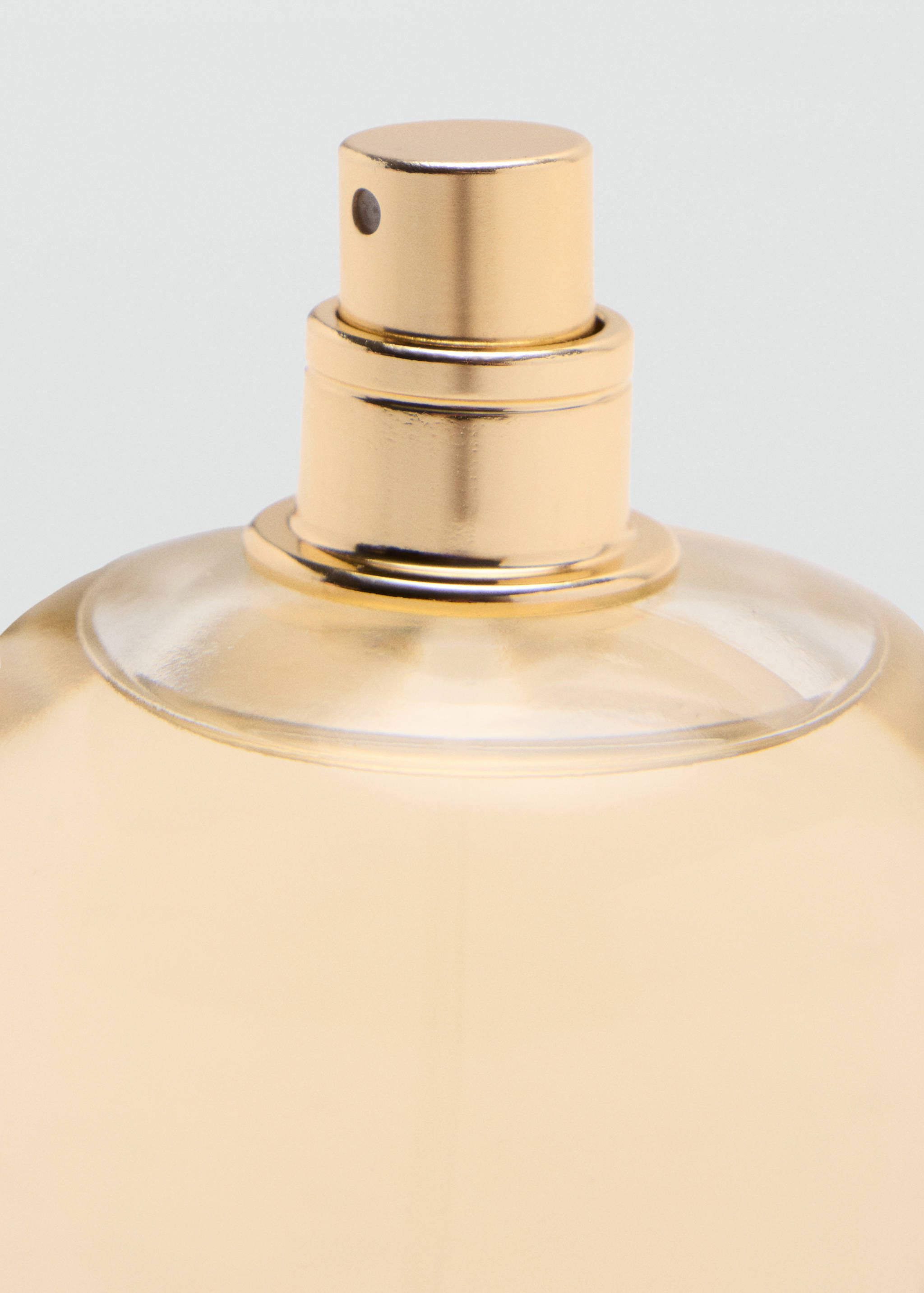 Close-up of a perfume bottle with a metallic gold spray nozzle.