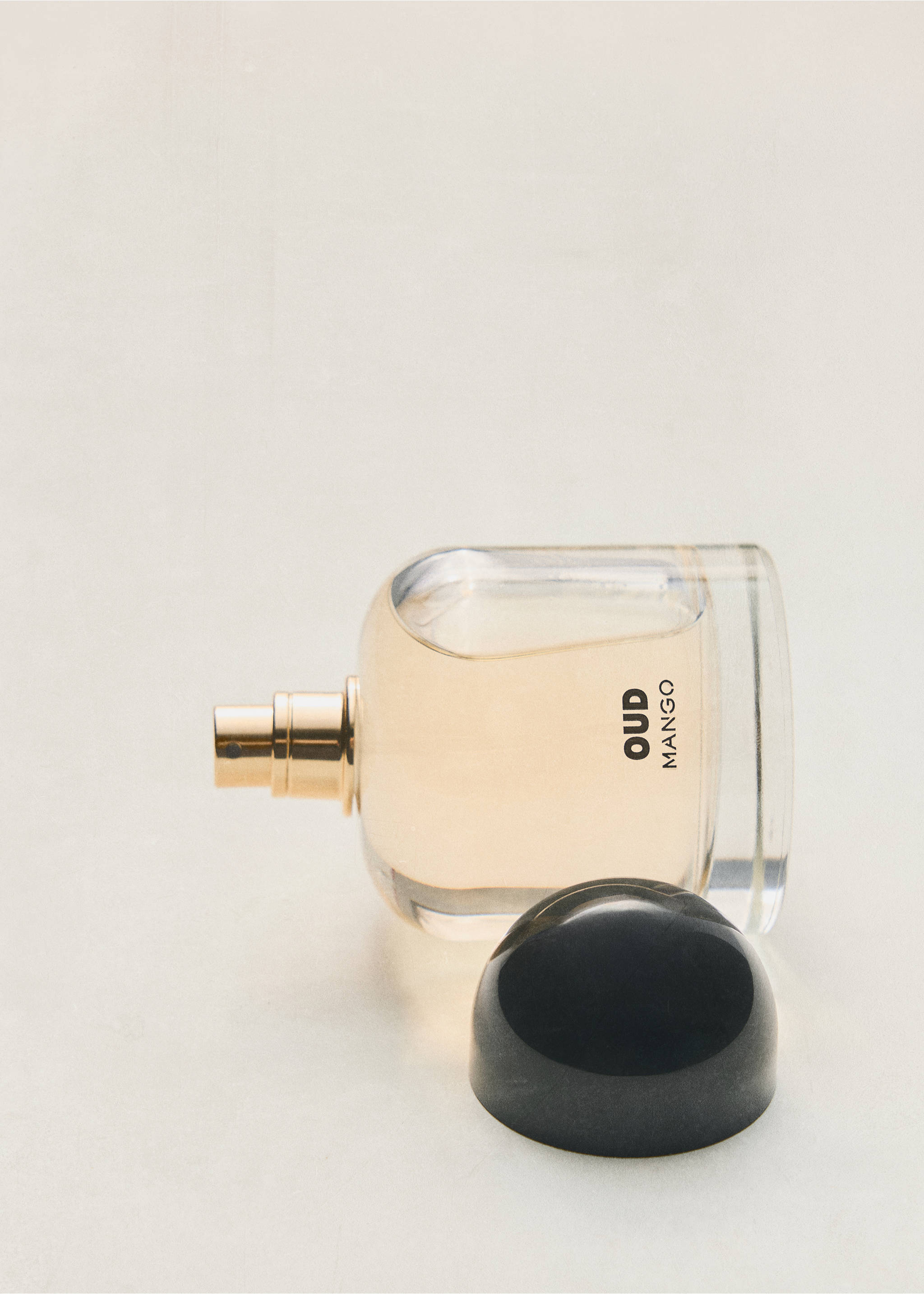 Oud perfume bottle with pale amber liquid, gold nozzle, and a dark rounded cap., Mink Grey. Ref: 47001457-00.