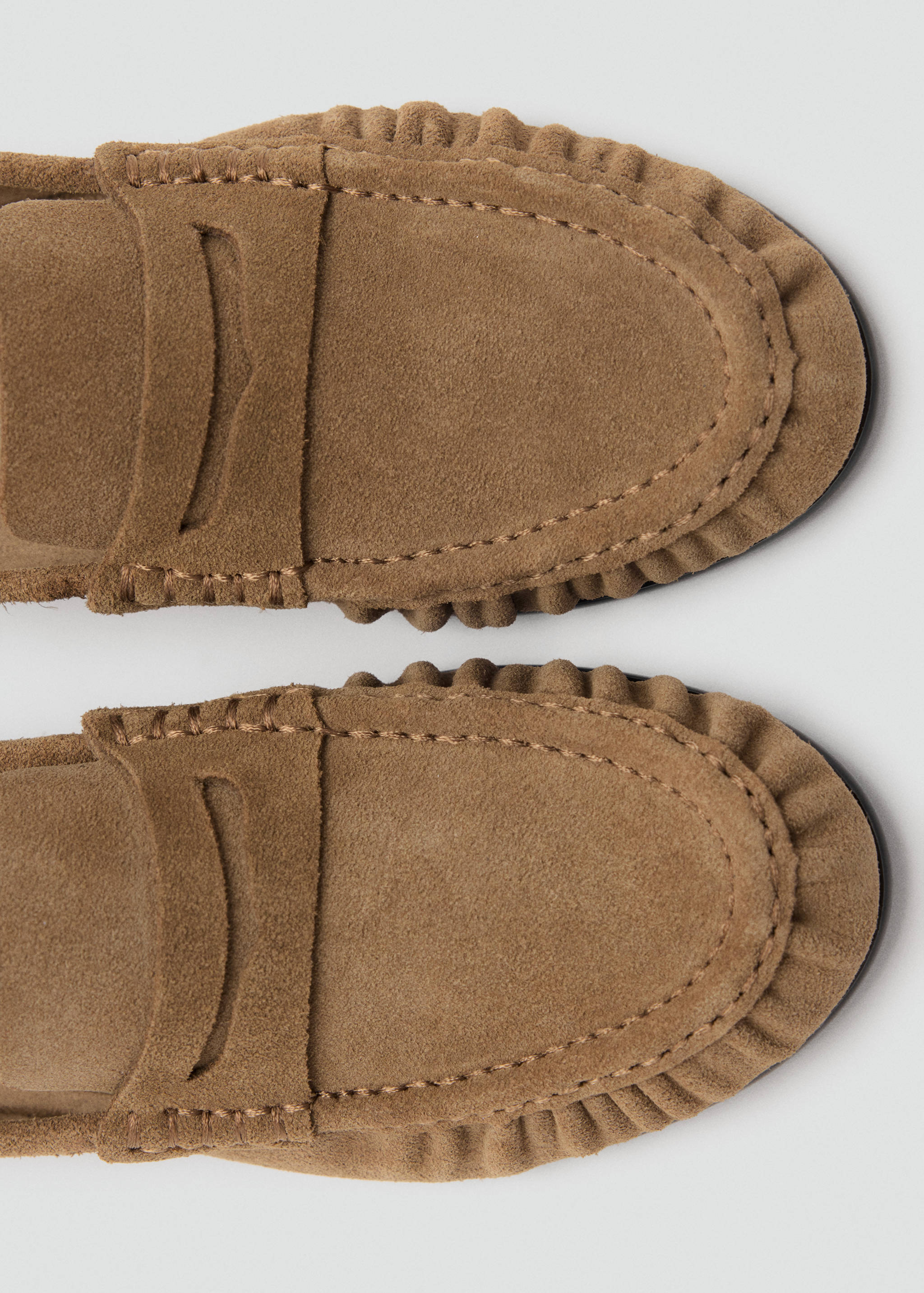 Brown suede loafer detail showing moccasin stitching and strap
