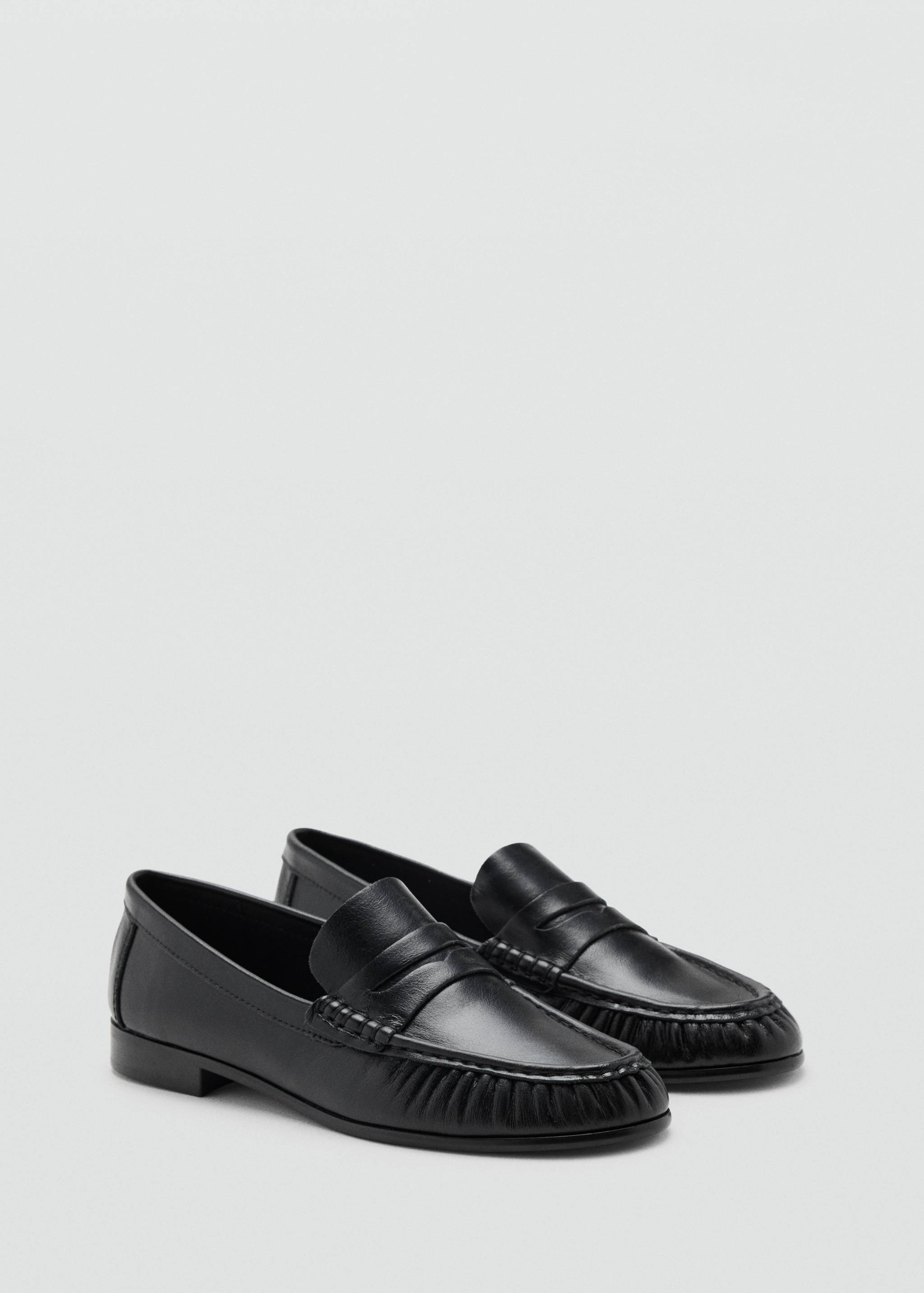 Mocasines de piel negros con antifaz y detalle fruncido en la puntera.