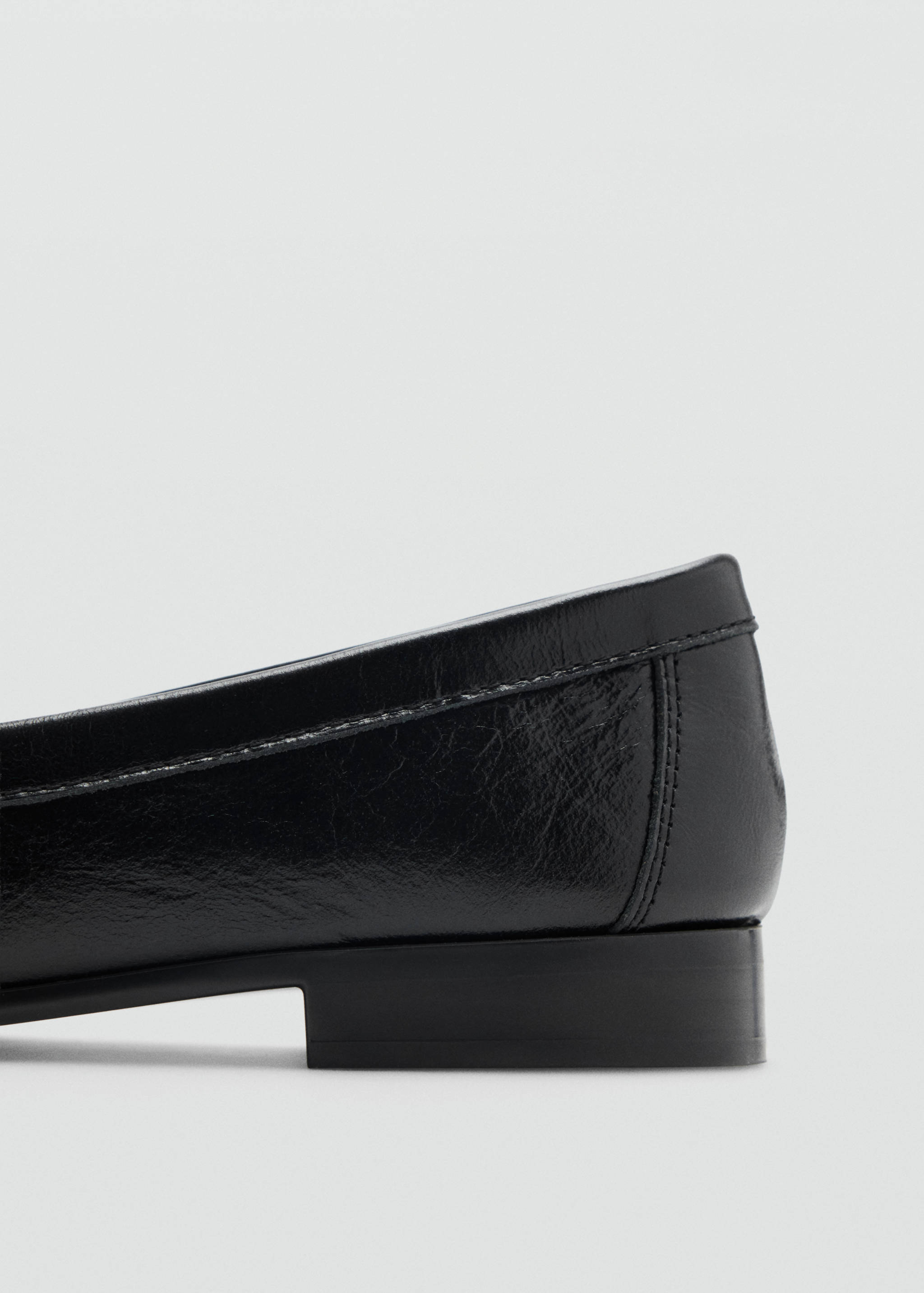Detalle del tacón de un zapato plano negro en primer plano.