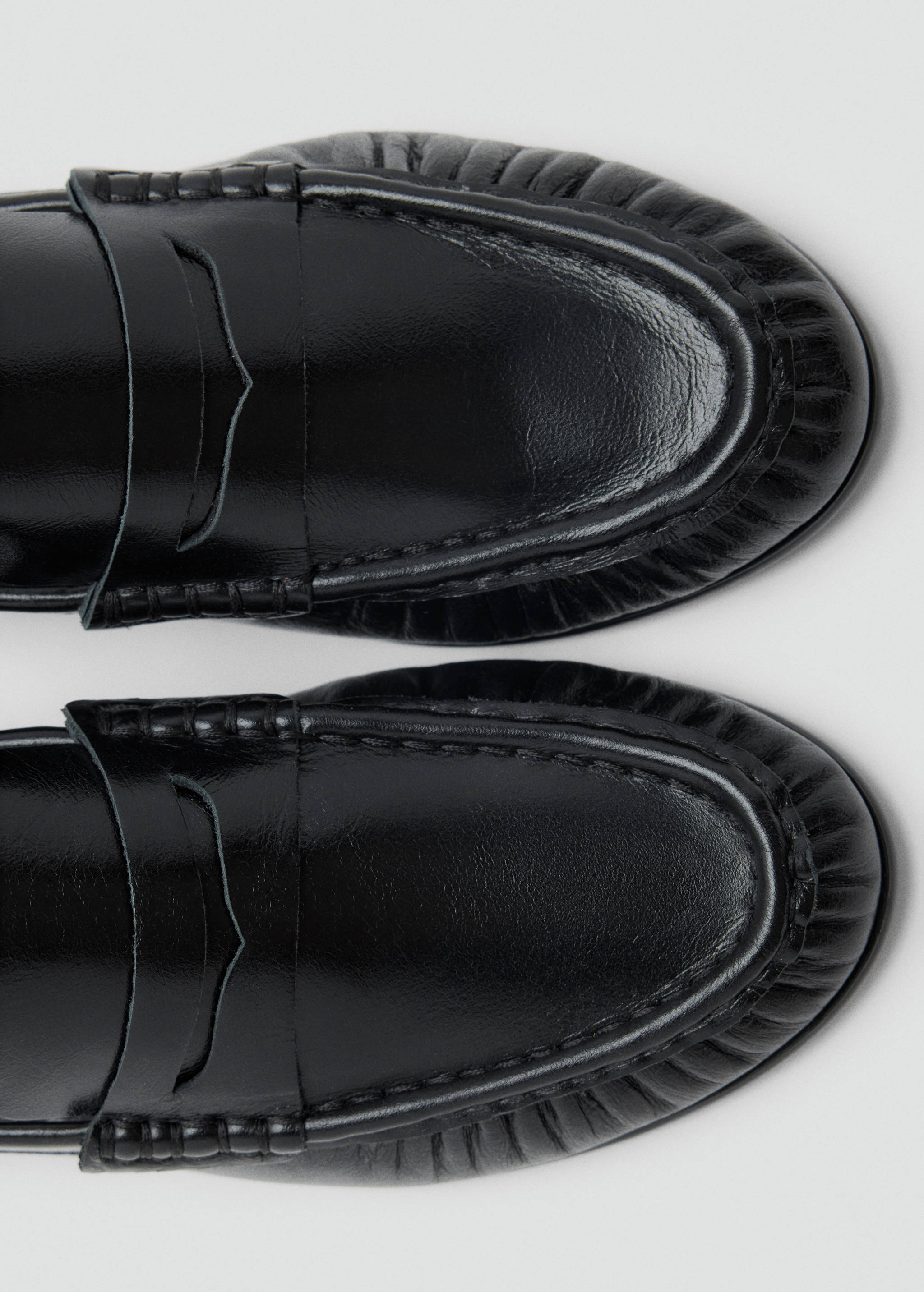 Detalle de la puntera y el empeine de unos mocasines negros de piel.