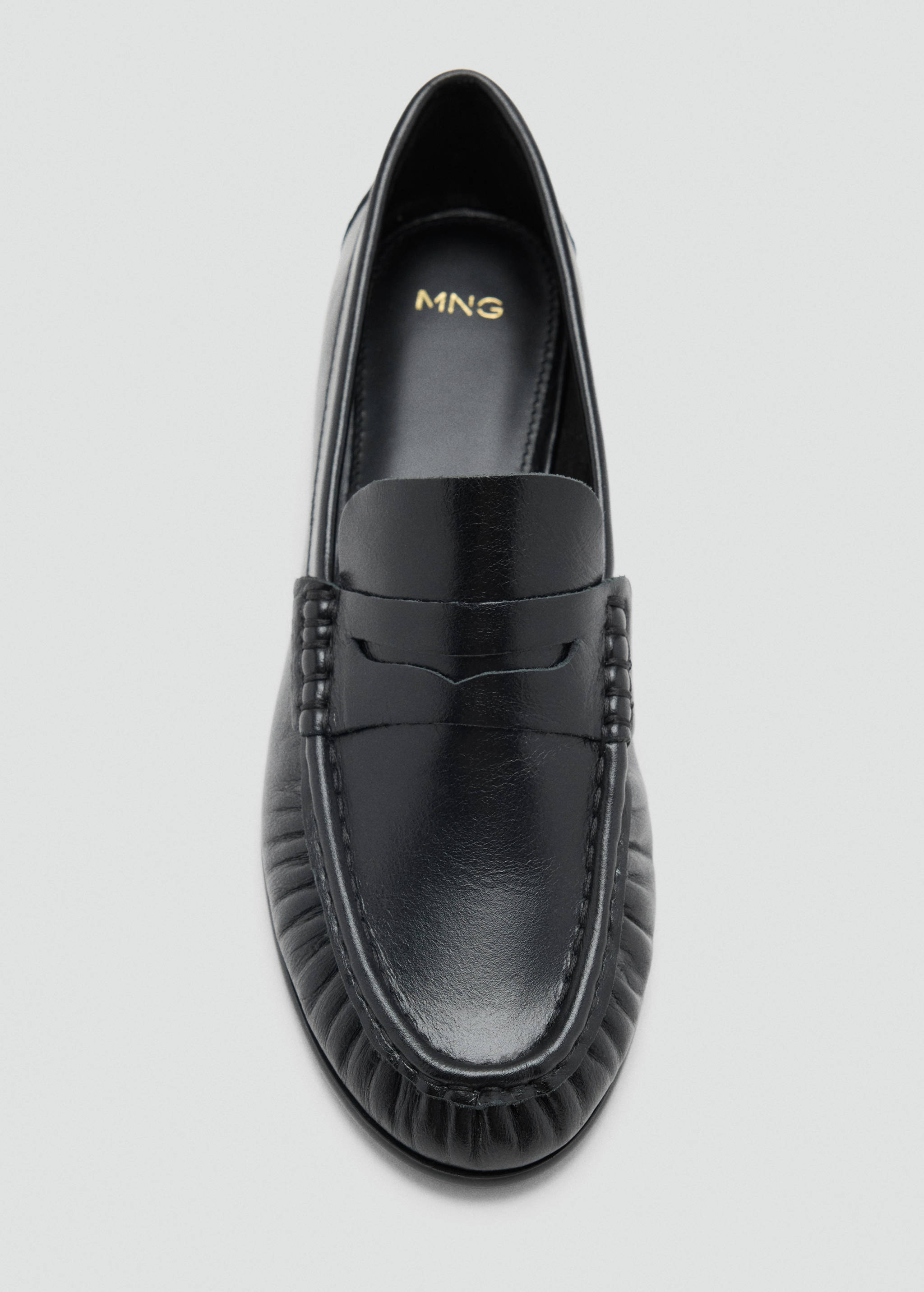 Zapato plano de piel en color negro con antifaz tradicional y detalle de costura marcada en la pala.