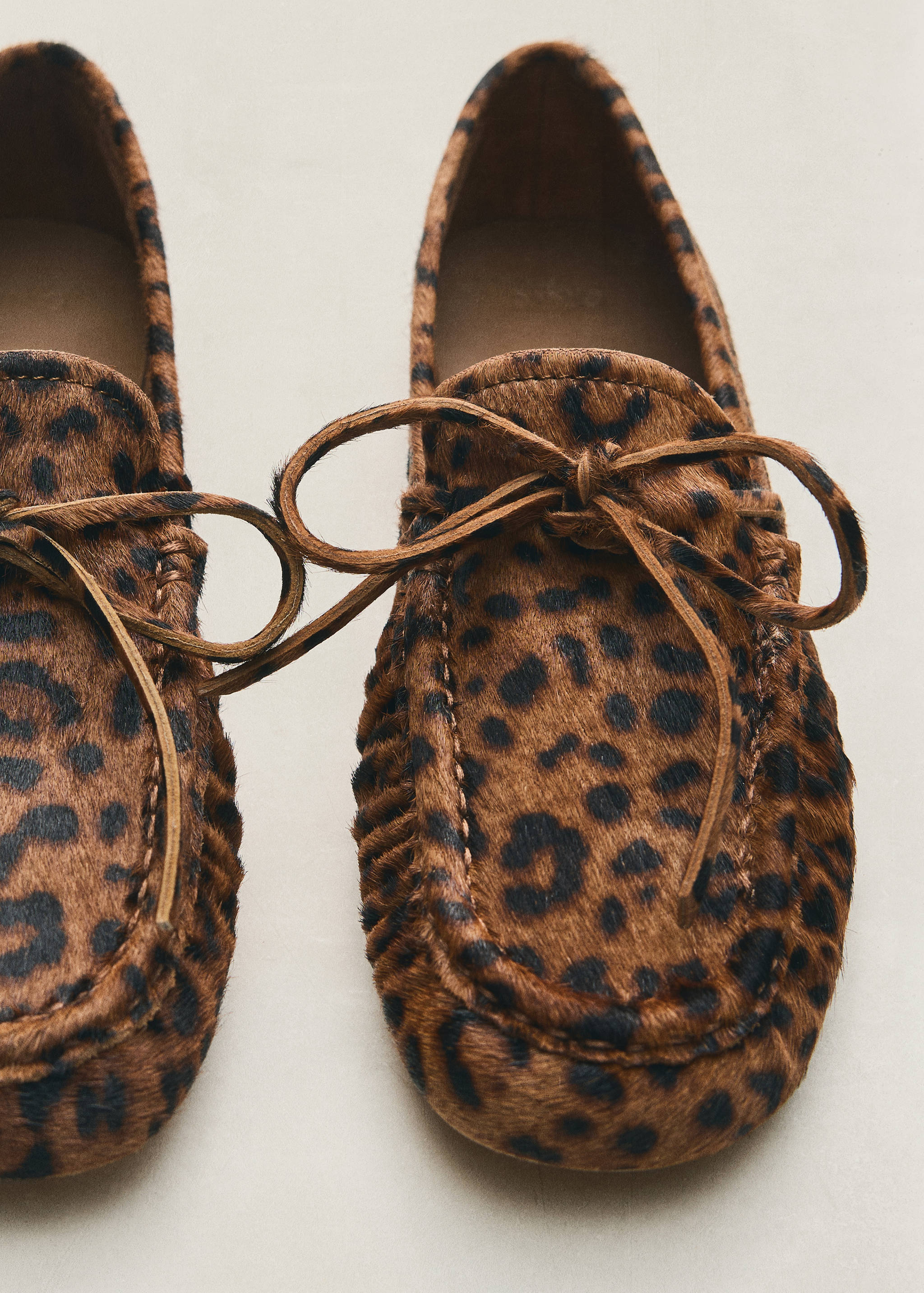 Leopard-print loafers with moccasin stitching and a front tie.