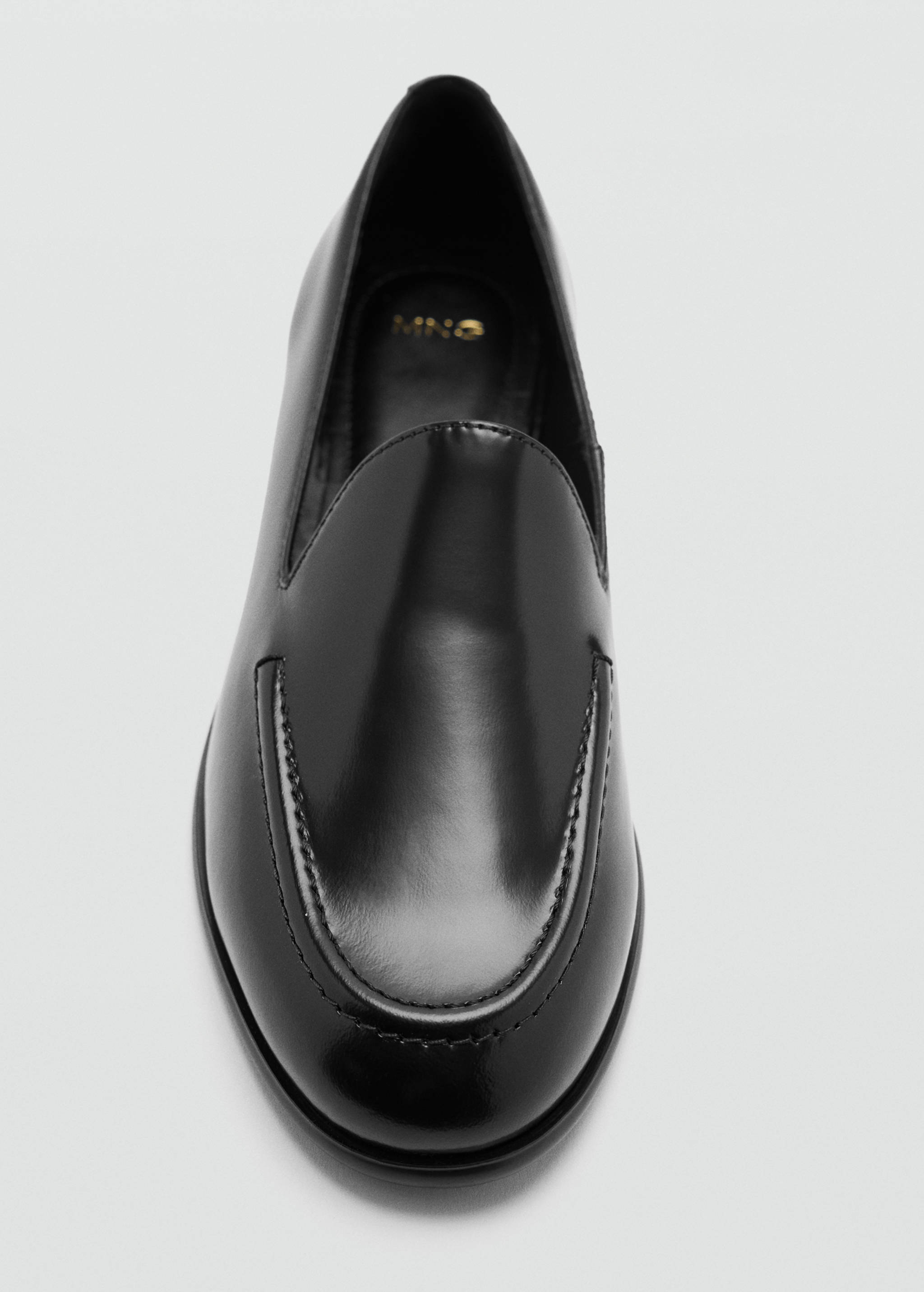 Zapato mocasín slip-on negro con acabado pulido y detalle de costura en el empeine.