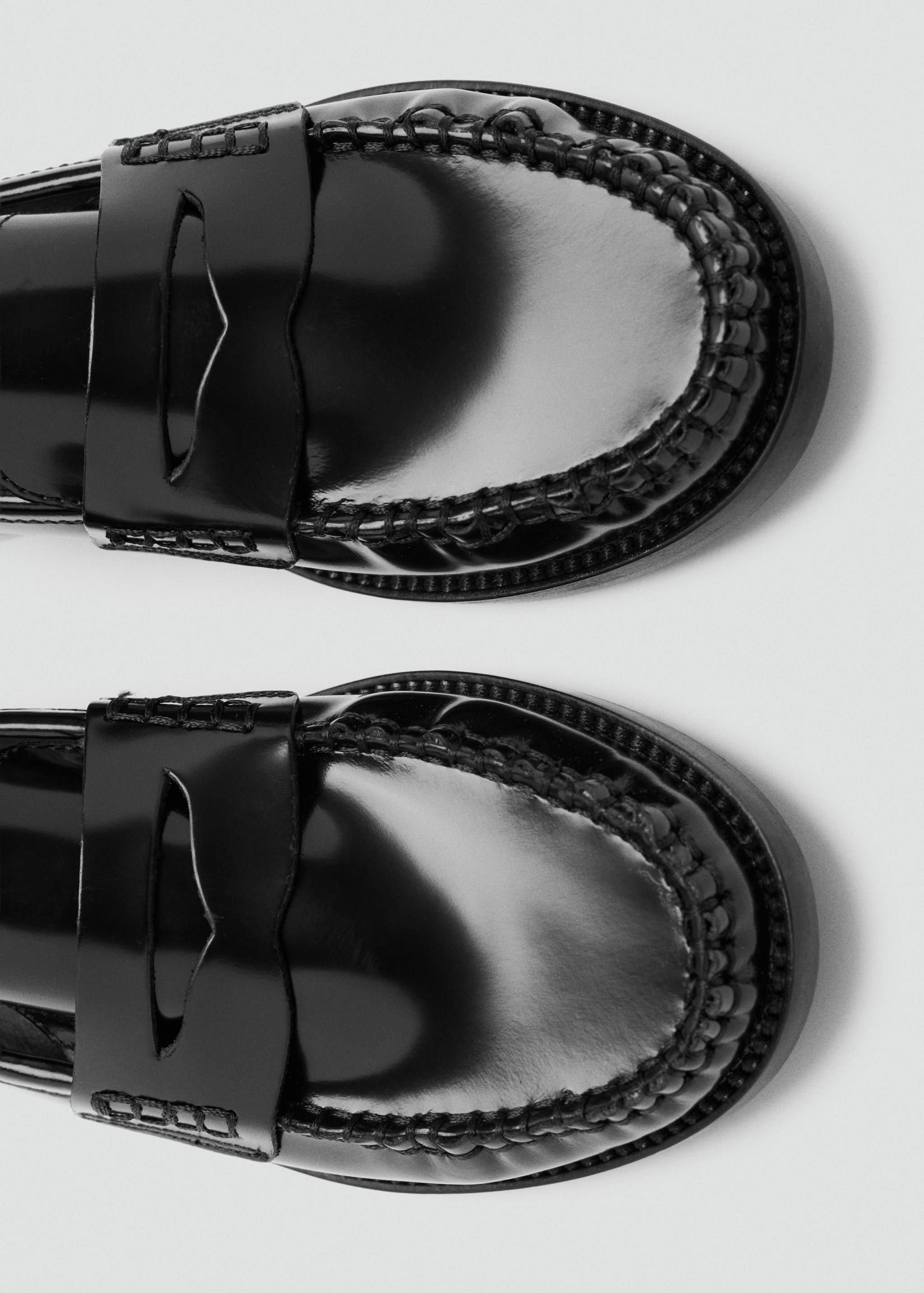 Close-up of black patent leather loafers with classic penny strap.