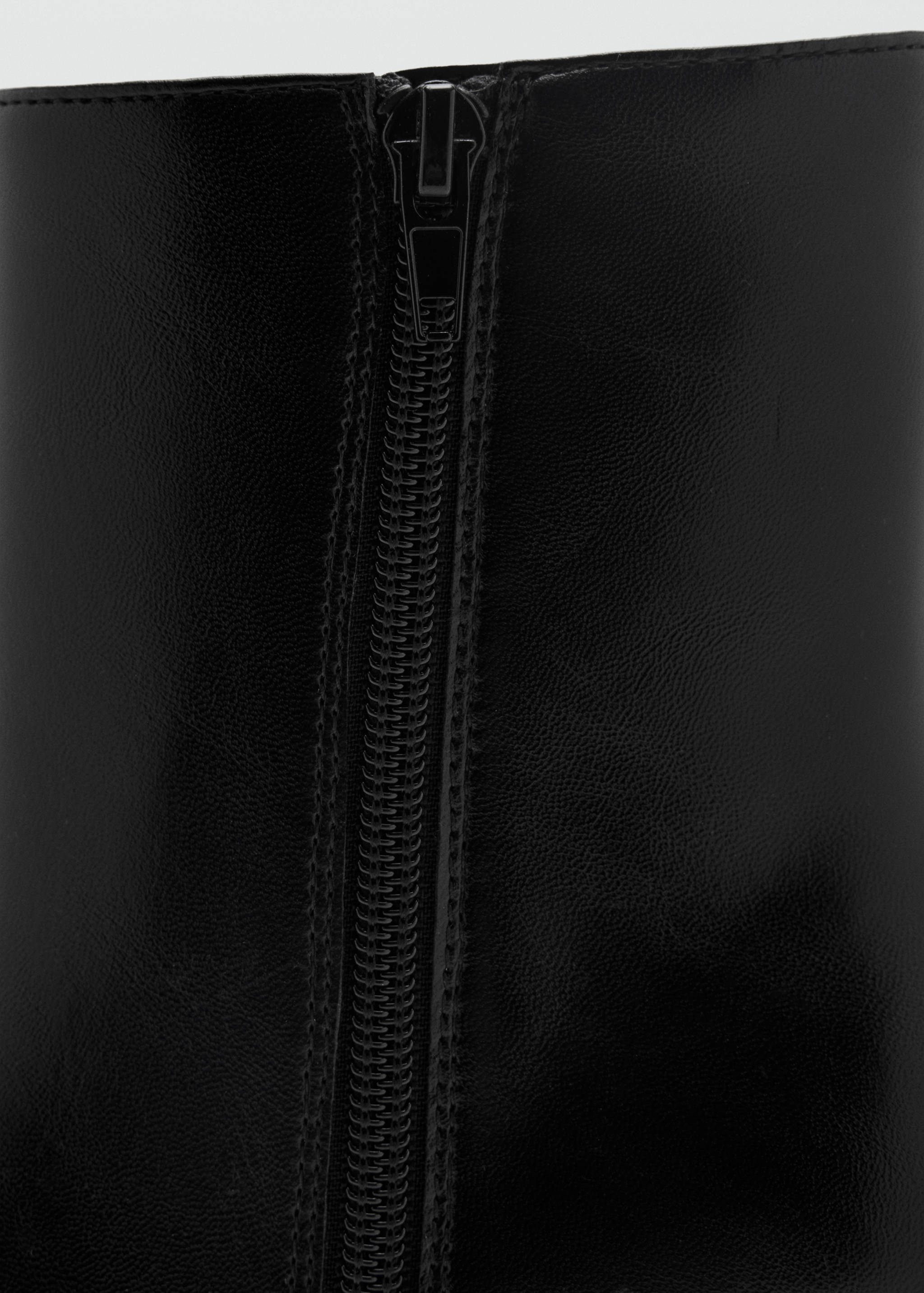 Close-up of the zipper detail on a black ankle boot.