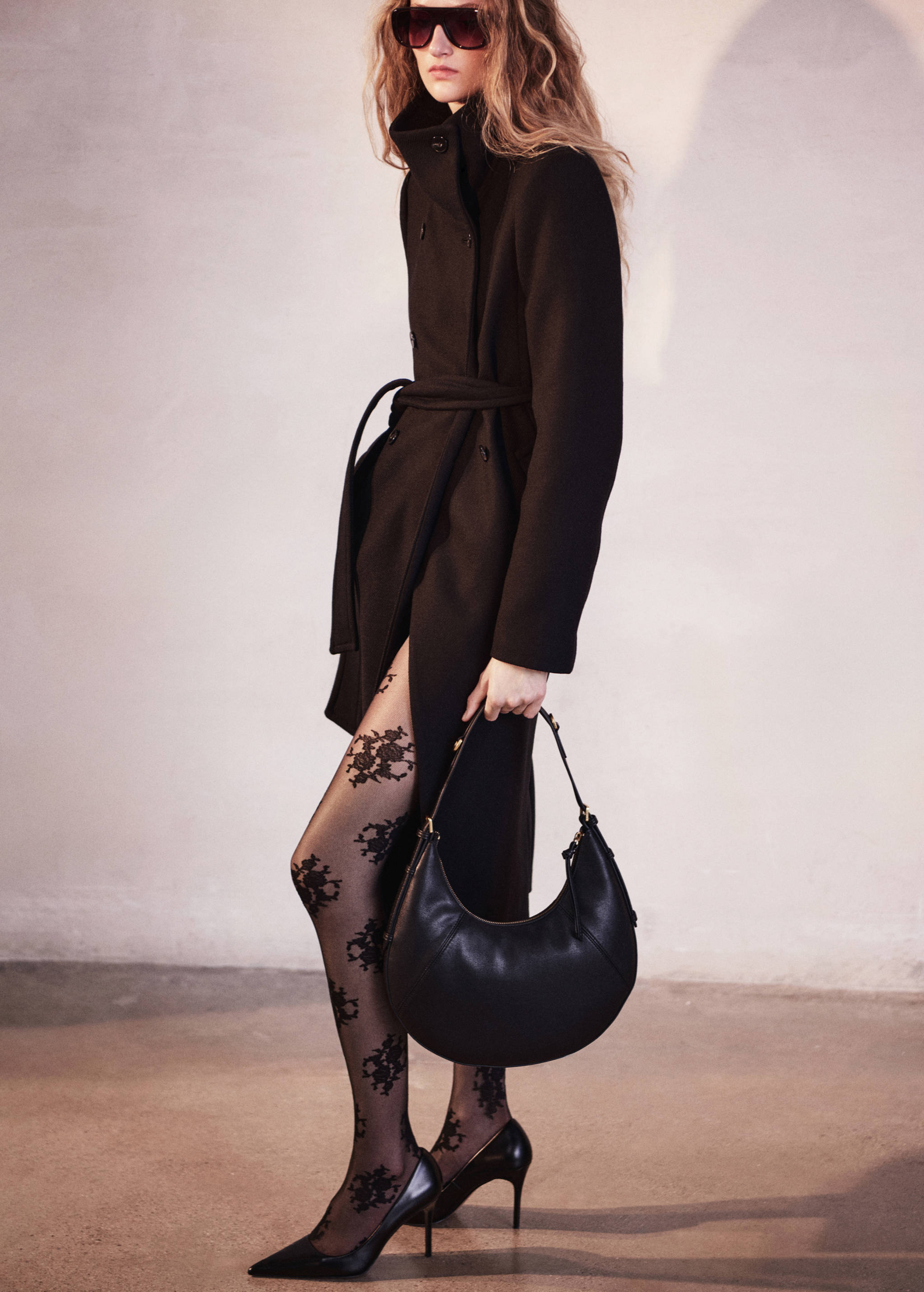 Bolso de hombro de piel negra con silueta curvada y herrajes dorados.