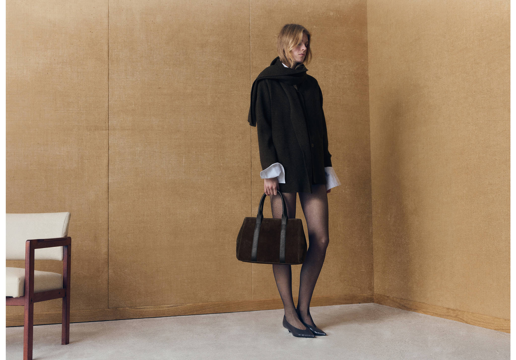 Dark brown city bag with twin top handles, held by a model.