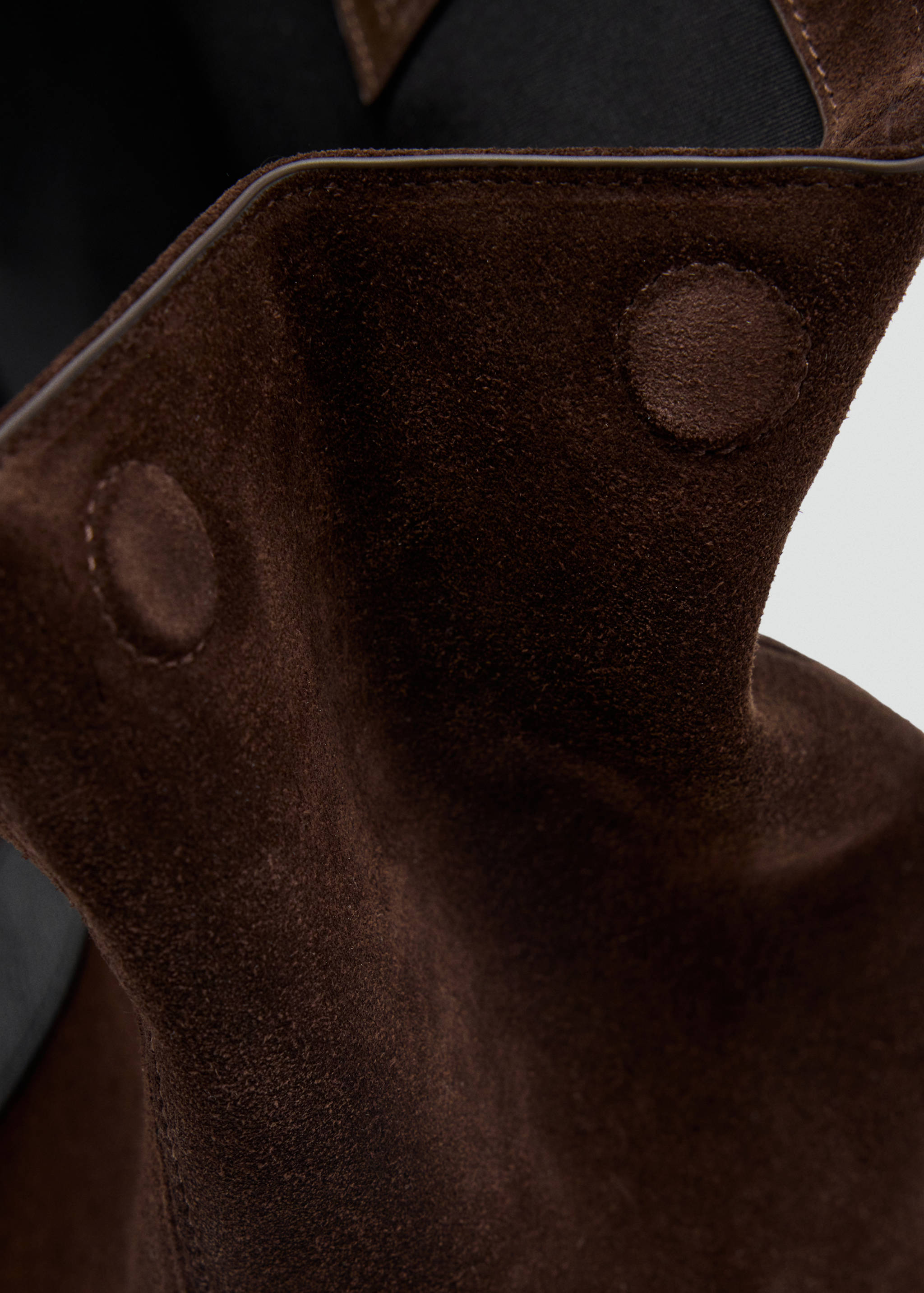 Close-up of the magnetic closure and dark brown suede texture of a city bag.