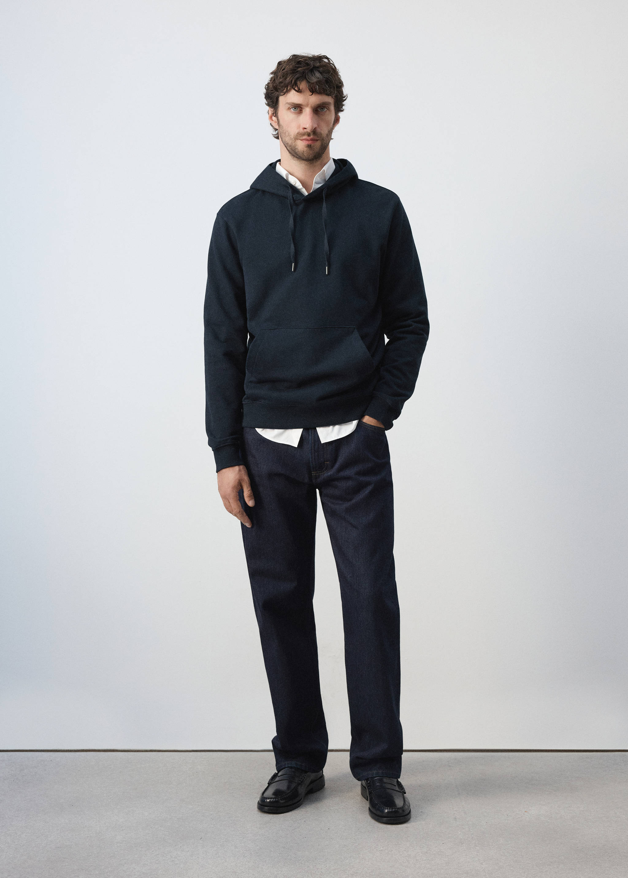 Navy blue hooded sweatshirt with a kangaroo pocket, worn layered over a white shirt.