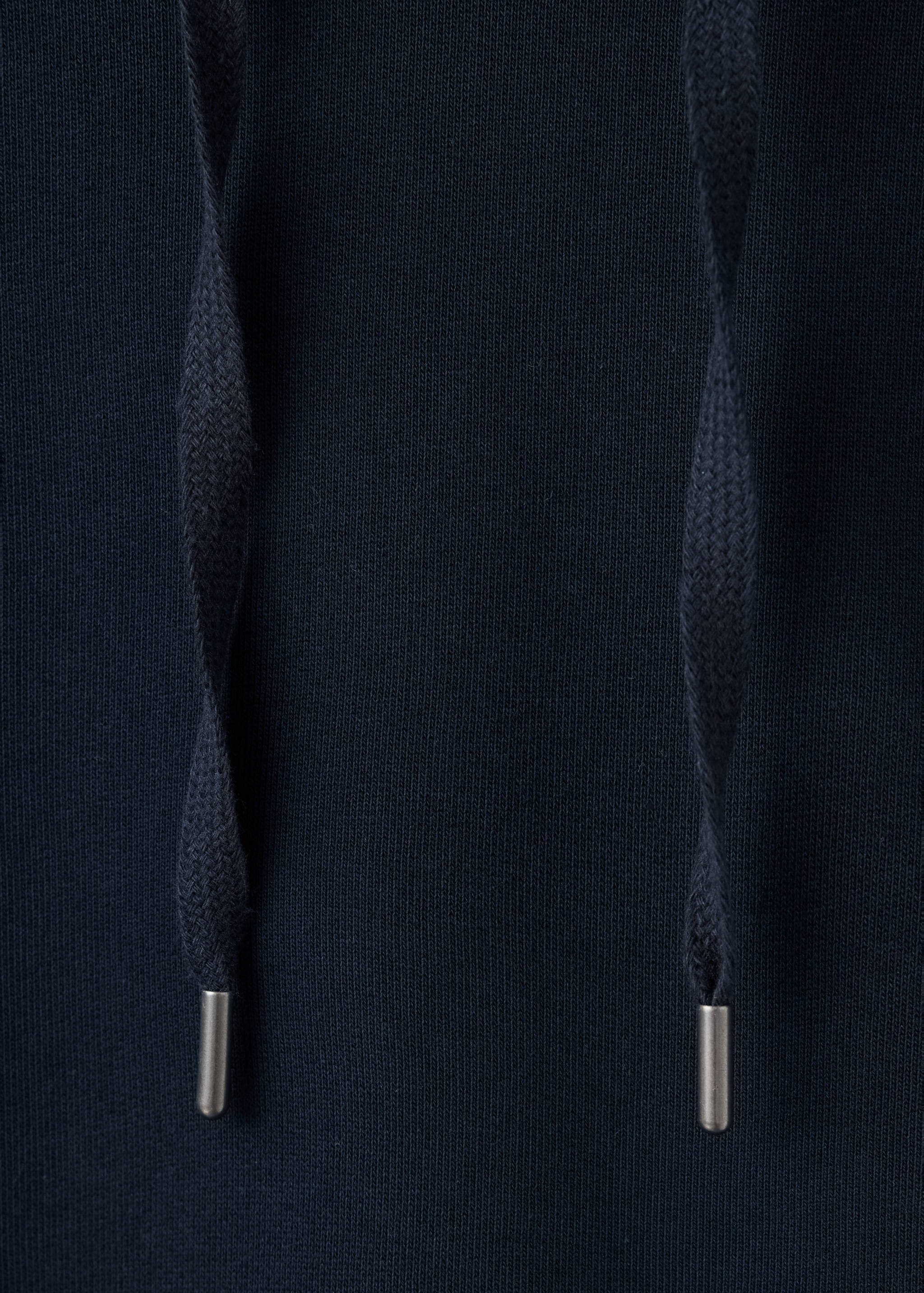 Close-up of a dark blue sweatshirt with drawstring cords and metal tips.