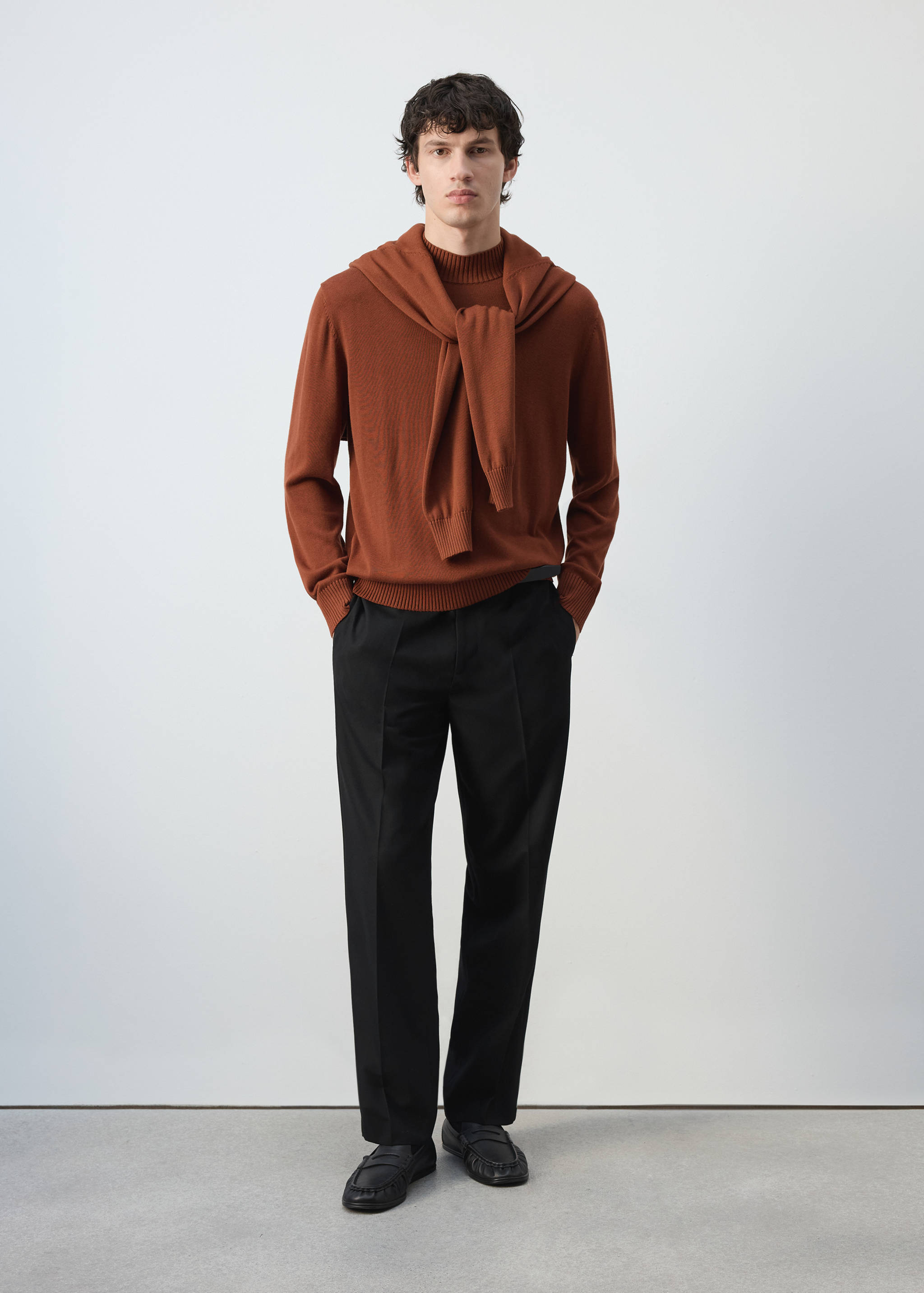 Rust-brown knitted jersey with a high neckline, styled with a matching sweater draped over the shoulders.
