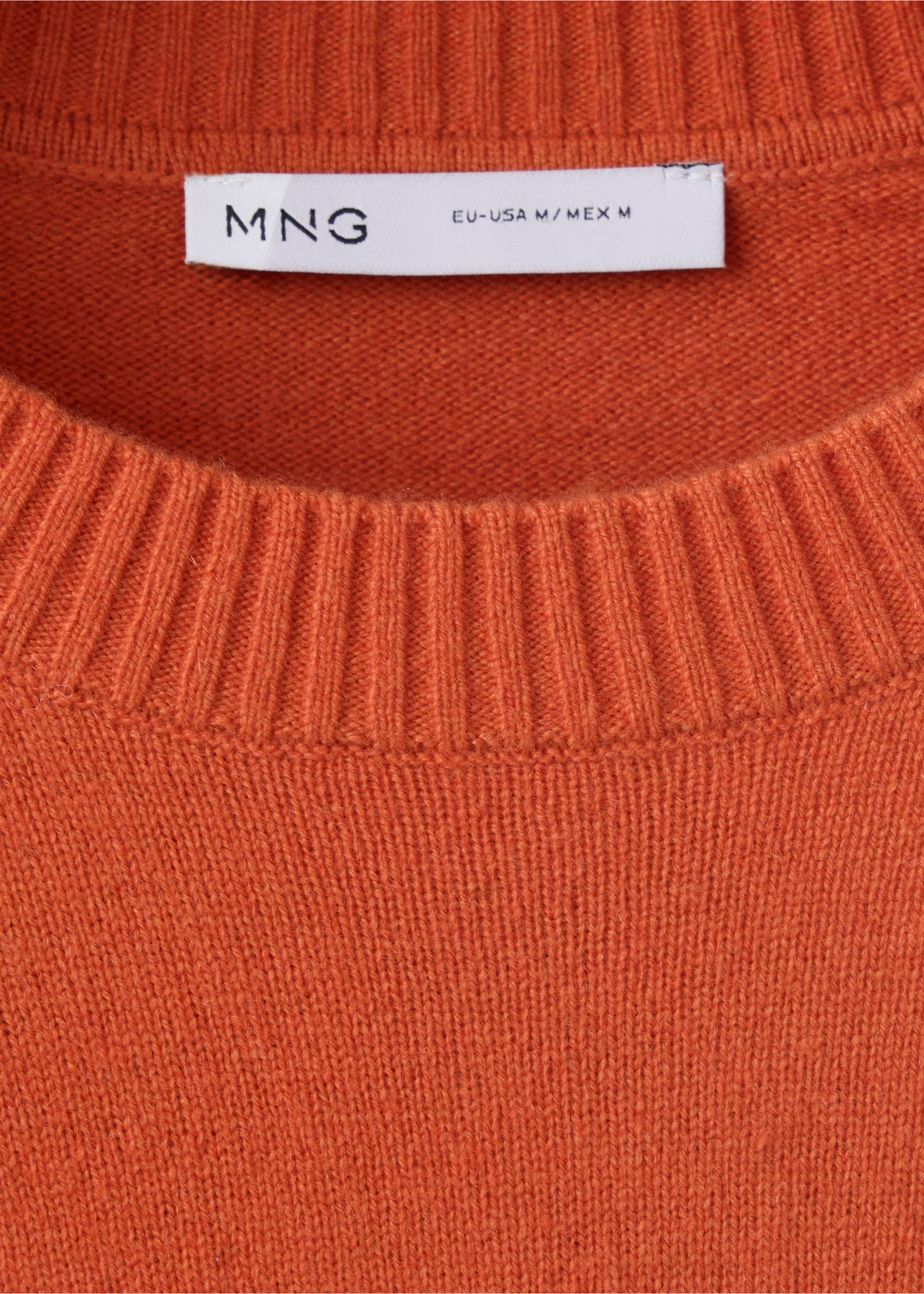 Primer plano de un jersey de punto naranja que muestra el cuello redondo de canalé y la etiqueta de la marca., Naranja. Ref: 47021336-00.