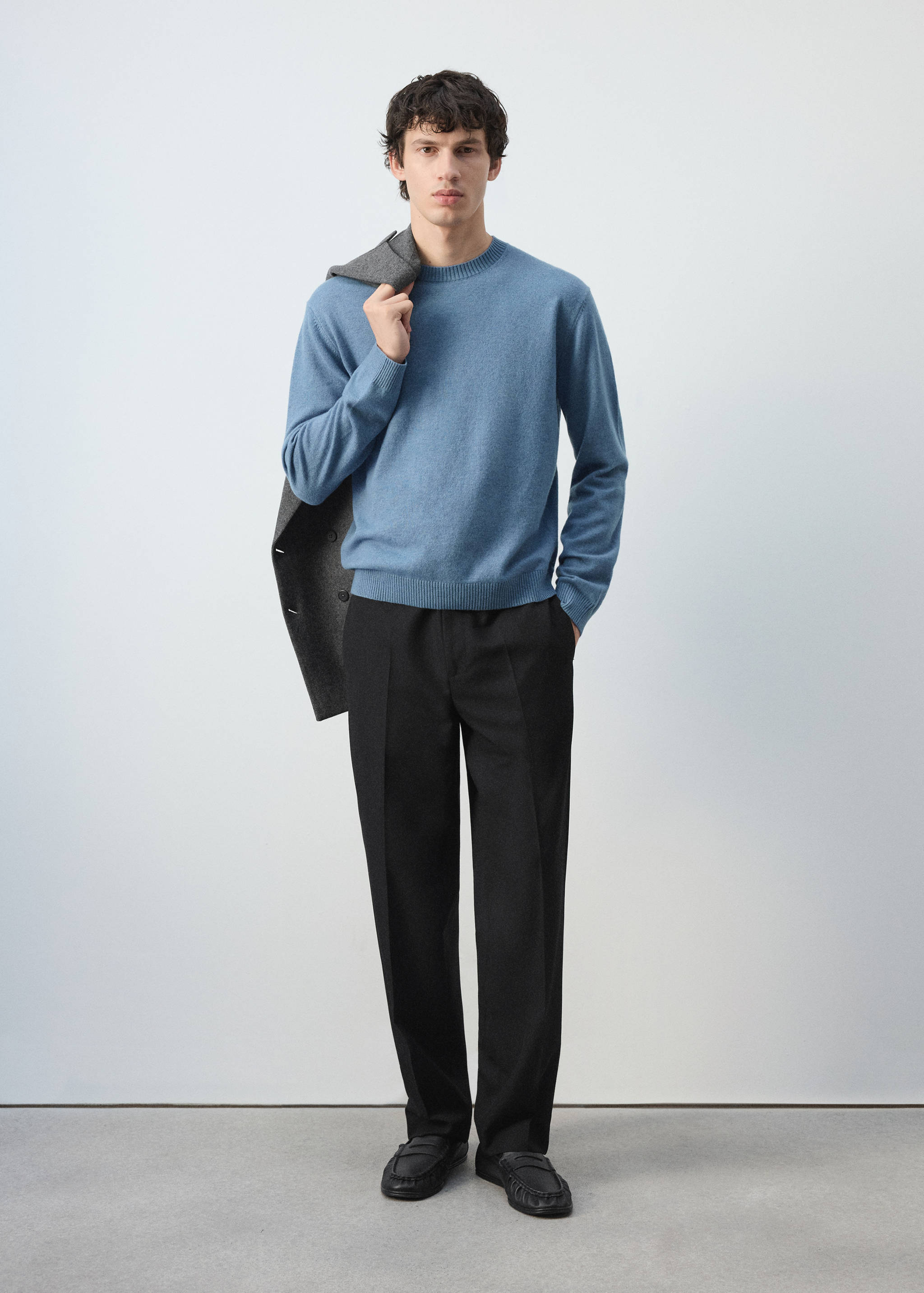 Jersey de cuello redondo azul claro combinado con pantalones negros y mocasines.