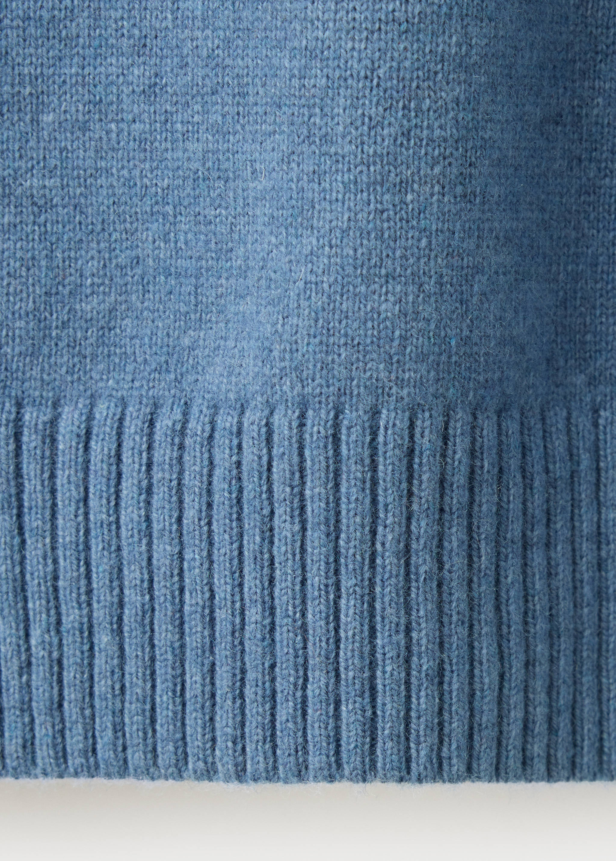 Primer plano de la textura de punto azul y el bajo de canalé de un jersey.