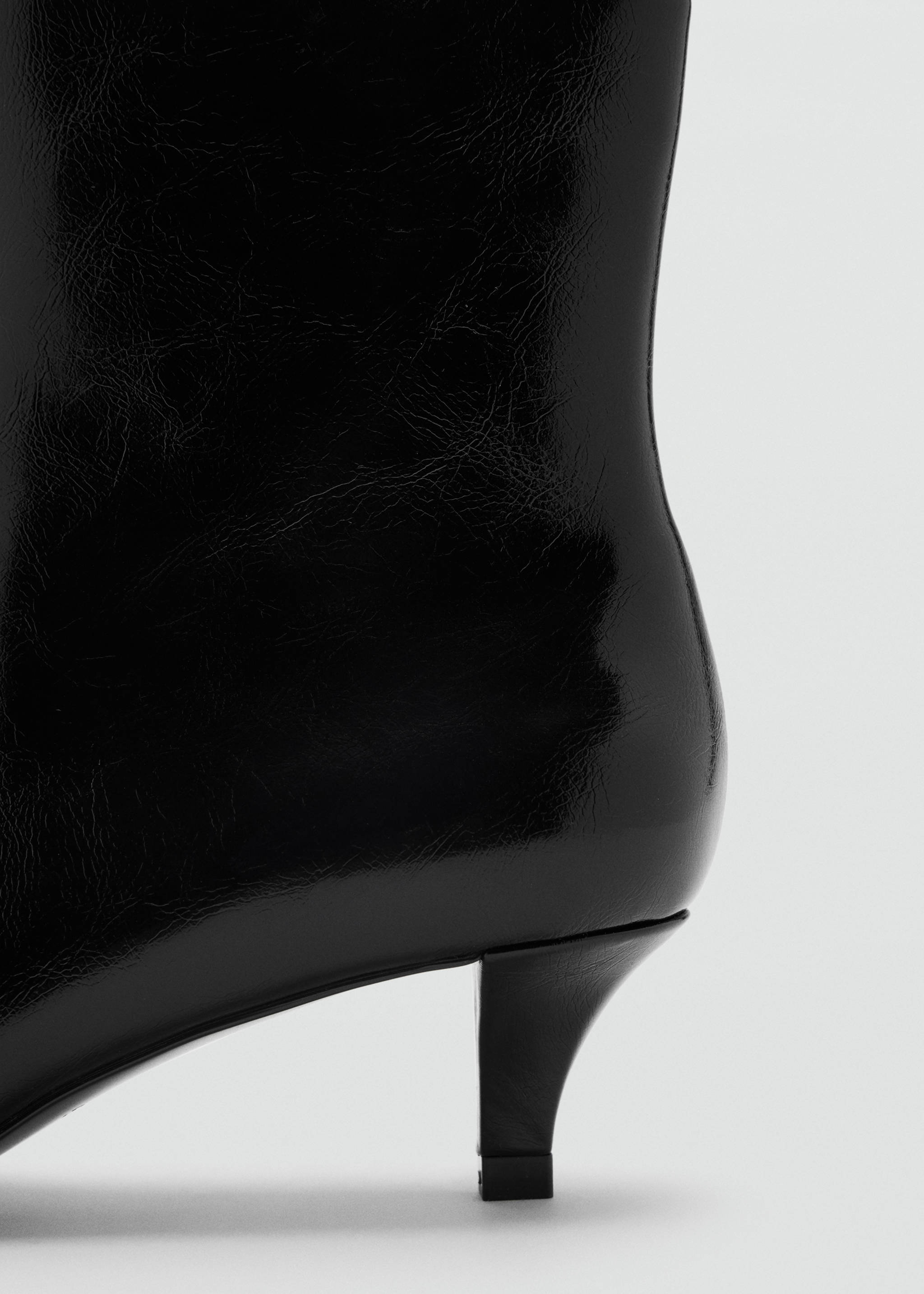 Close-up of a black patent ankle boot with a kitten heel.